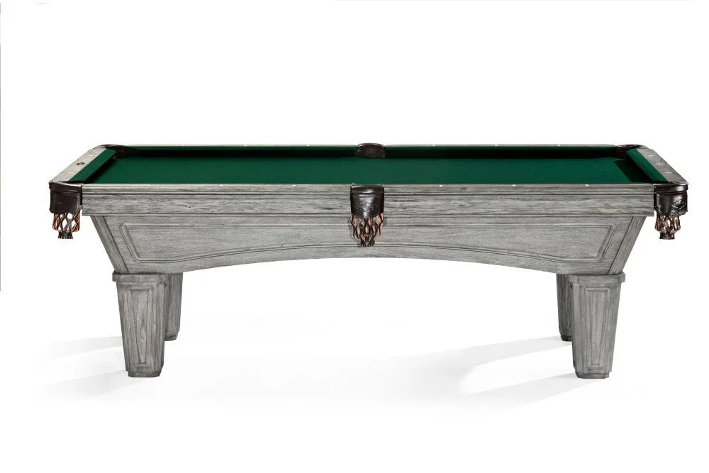 A miniature pool table with a rustic gray wooden frame, green felt surface, and dark leather corner pockets.