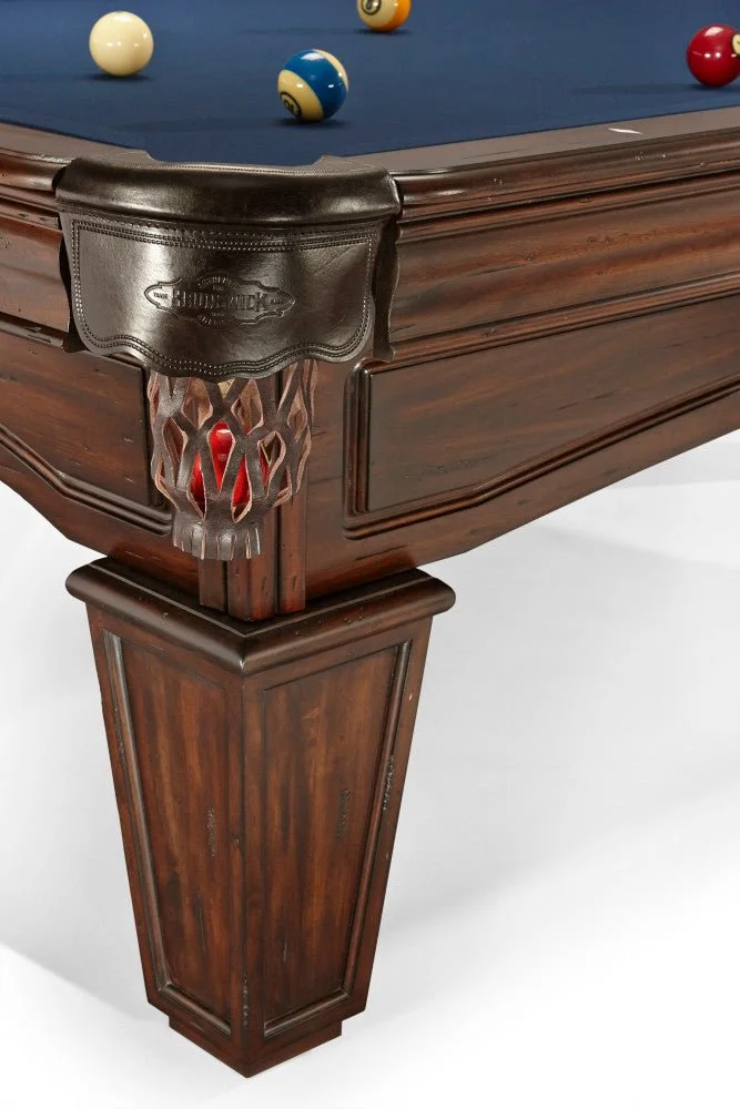 Close-up of a wooden billiards table corner with billiard balls on the felt and a leather corner pocket.
