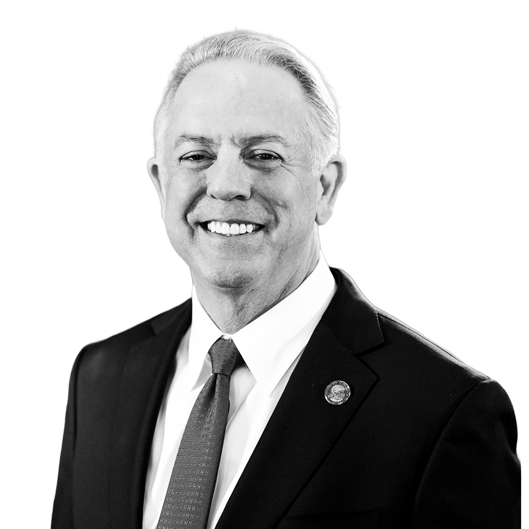 Black and white professional portrait of a smiling man in a suit and tie.