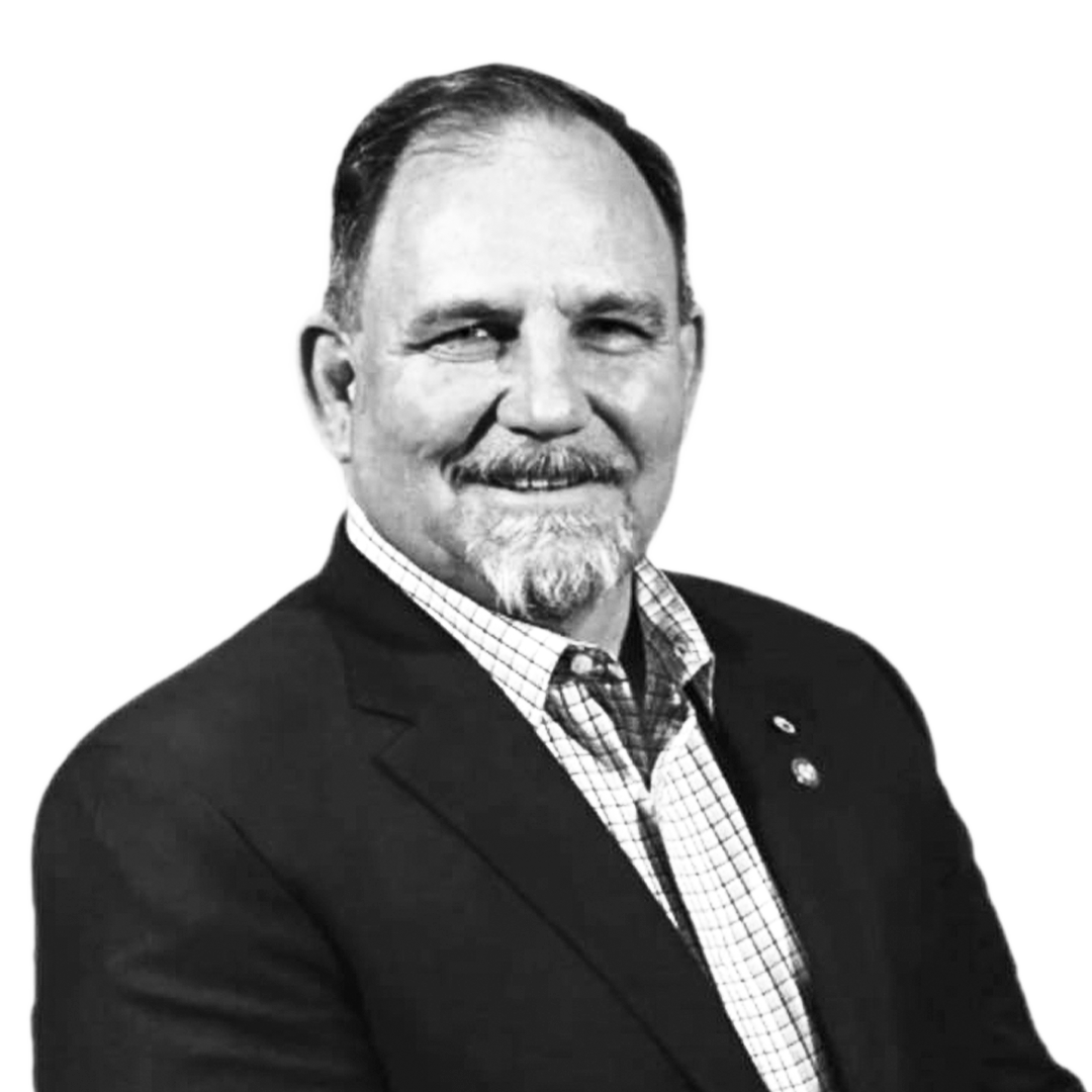 Black and white portrait of a middle-aged man with a mustache, beard, and short hair, wearing a suit jacket and a checkered shirt.