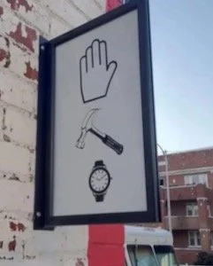 Sign showing a raised hand, a hammer, and a wristwatch