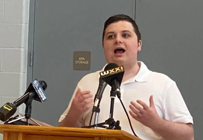 Male talking into microphone podium advocating for people with disabilities. 