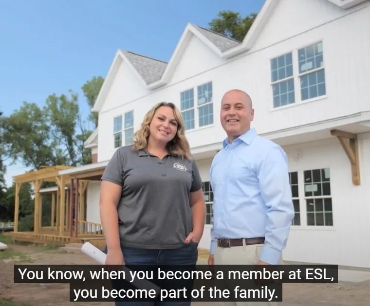 Founder Jenny Brongo standing in front of the completed Forever Homestead Community Center with a male from ESL. 