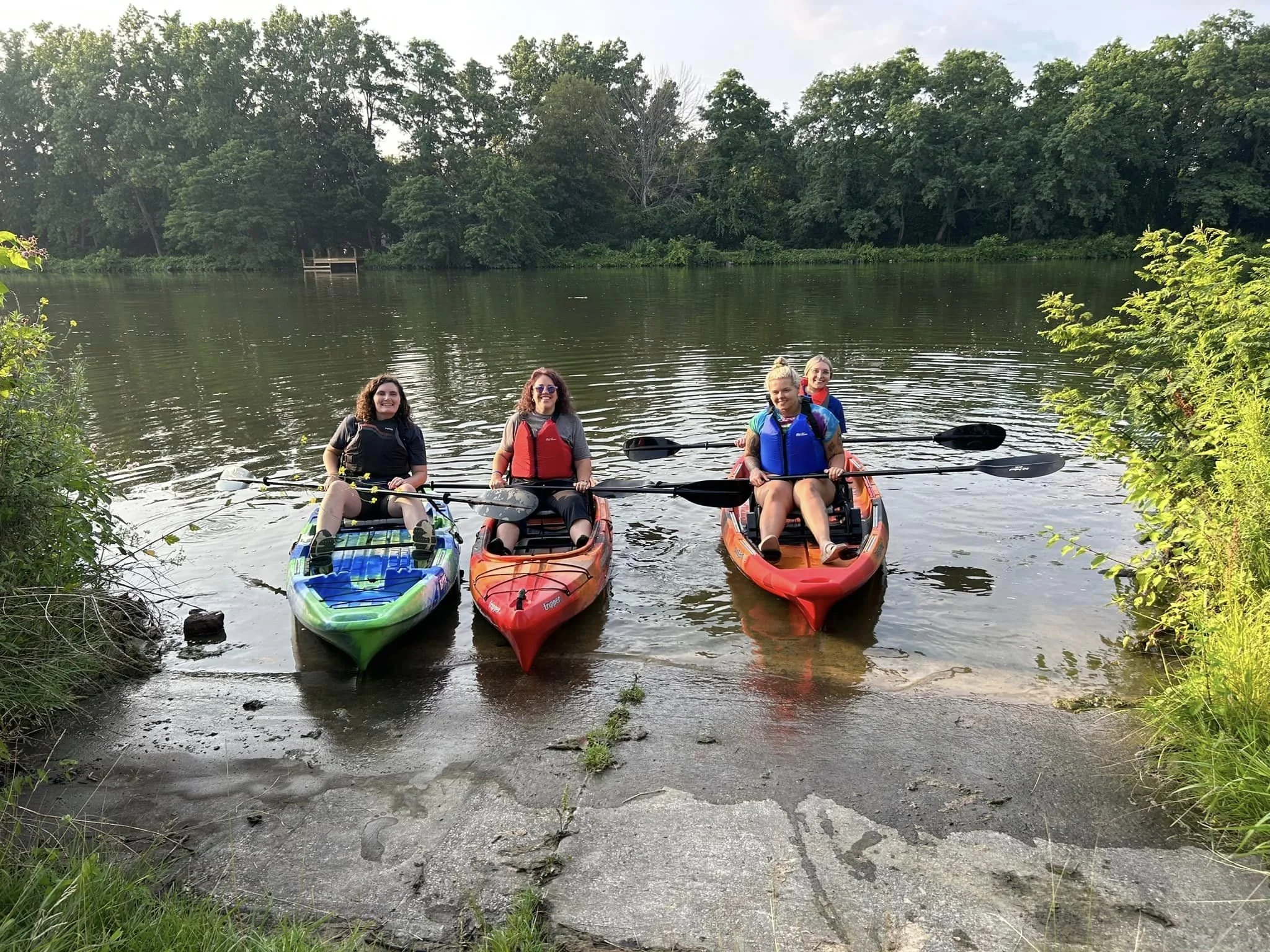 Four People in Kayaks paddling to shore in the Erie Canal. Accessible kayaking.