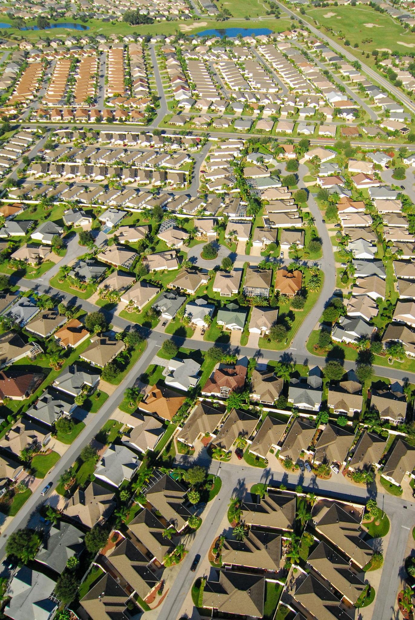 Central Florida High-angle aerial view of a densely packed suburban neighborhood with uniform single-family homes and winding roads.