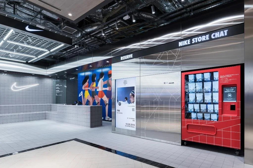Nike store interior with a check-in kiosk, digital display, and Nike merchandise vending machine.