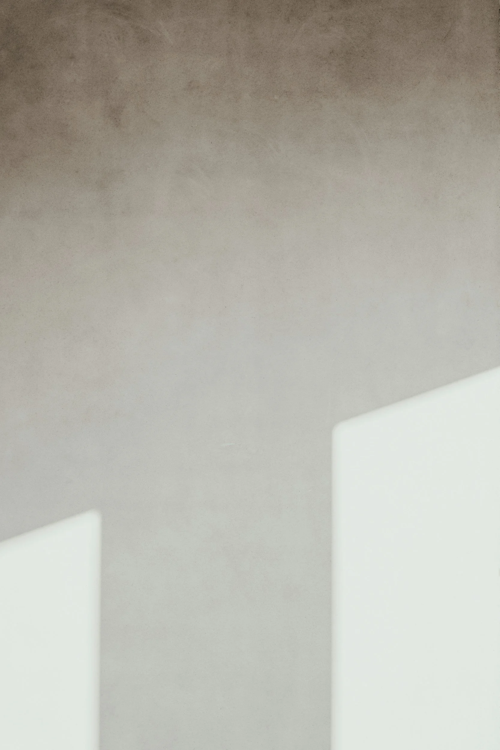 Close-up of two white architectural panels or partitions against a textured beige wall with soft lighting.