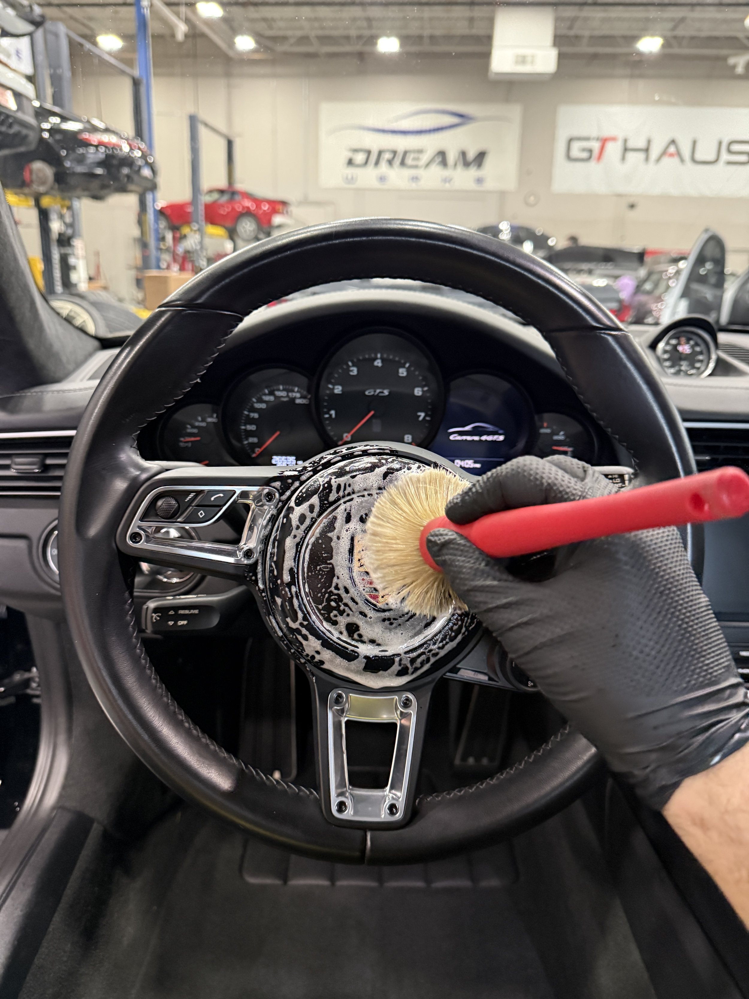 Person cleaning steering wheel with a brush in a car repair shop.