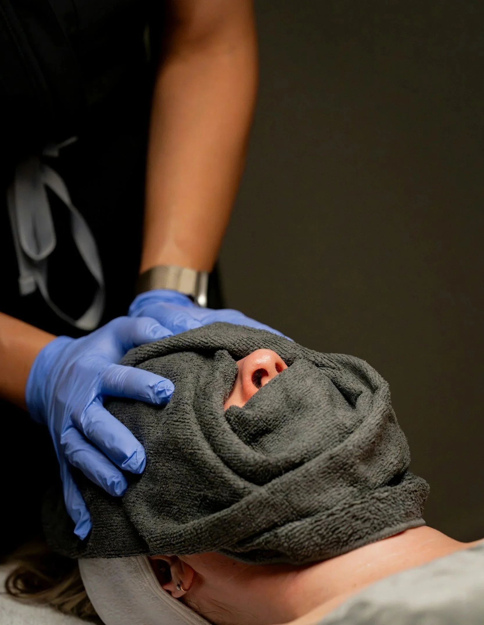 A person receiving a medical examination with a healthcare professional wearing blue gloves placed on their neck.