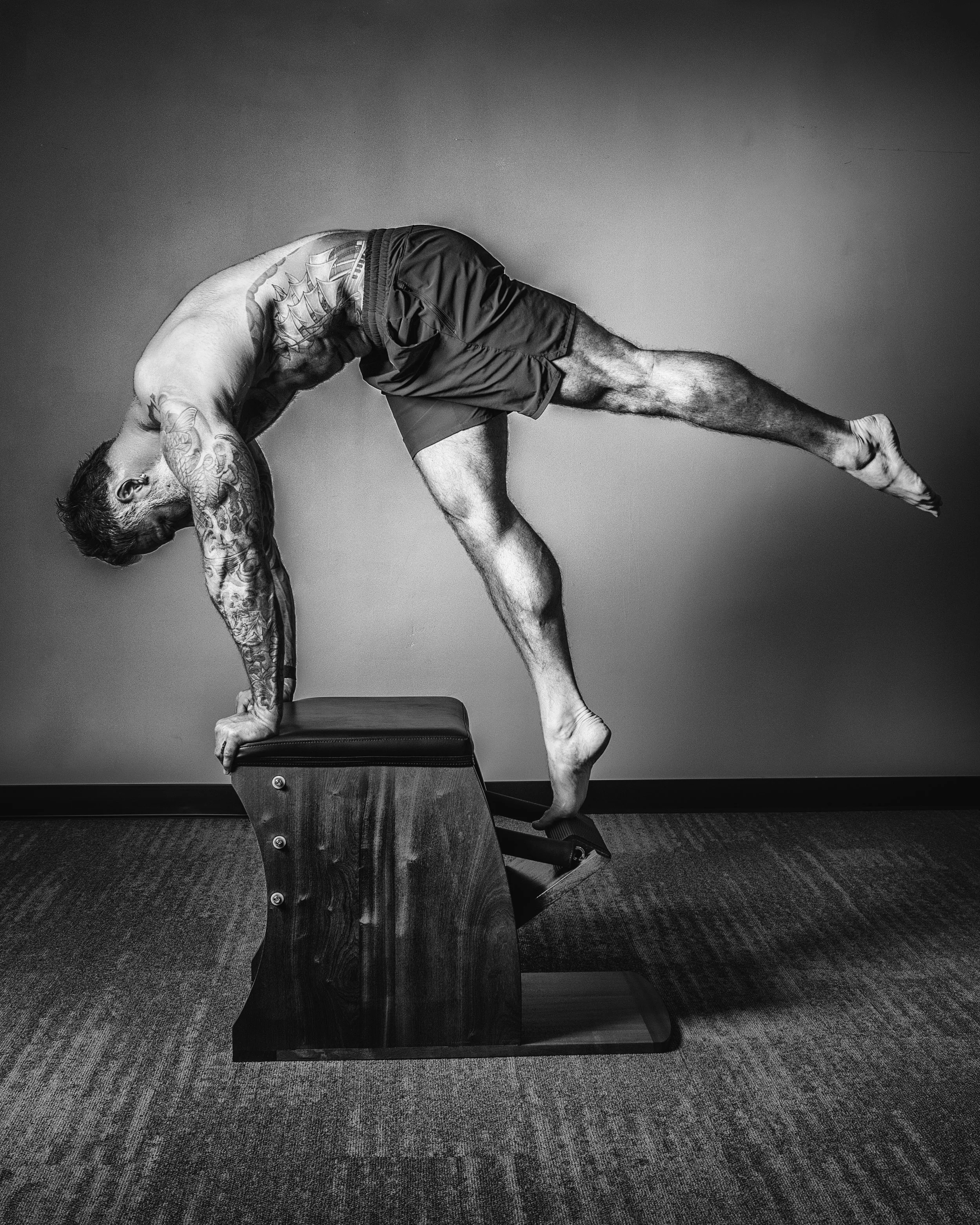 Stylized black and white photo of Mike Kyser demonstrating full body control as a result of pilates and mobility work for the purpose of instruction both online and in person. Membership platform and community available worldwide.