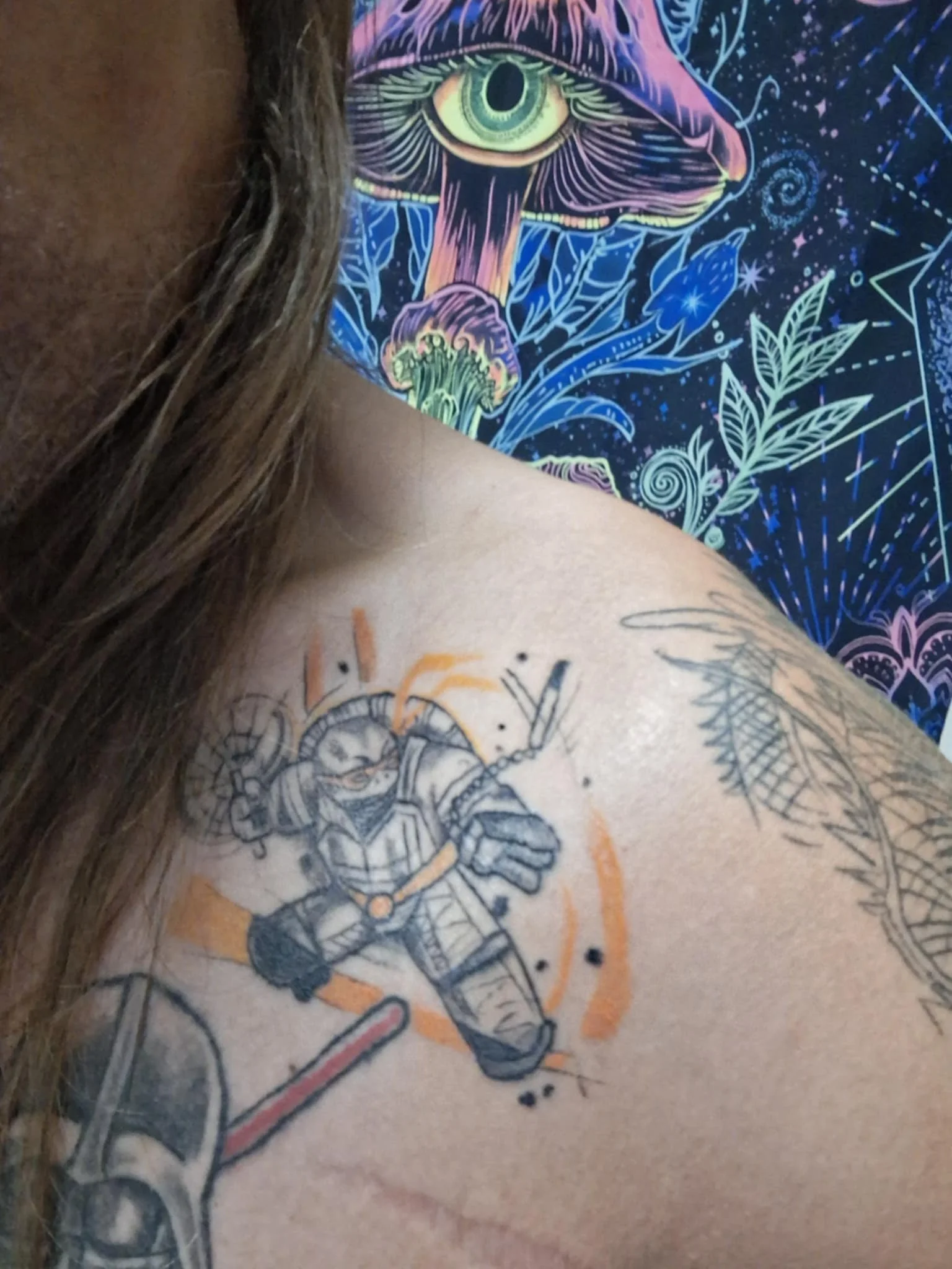 Tattoo of a cartoon astronaut with a shield on a person's shoulder.