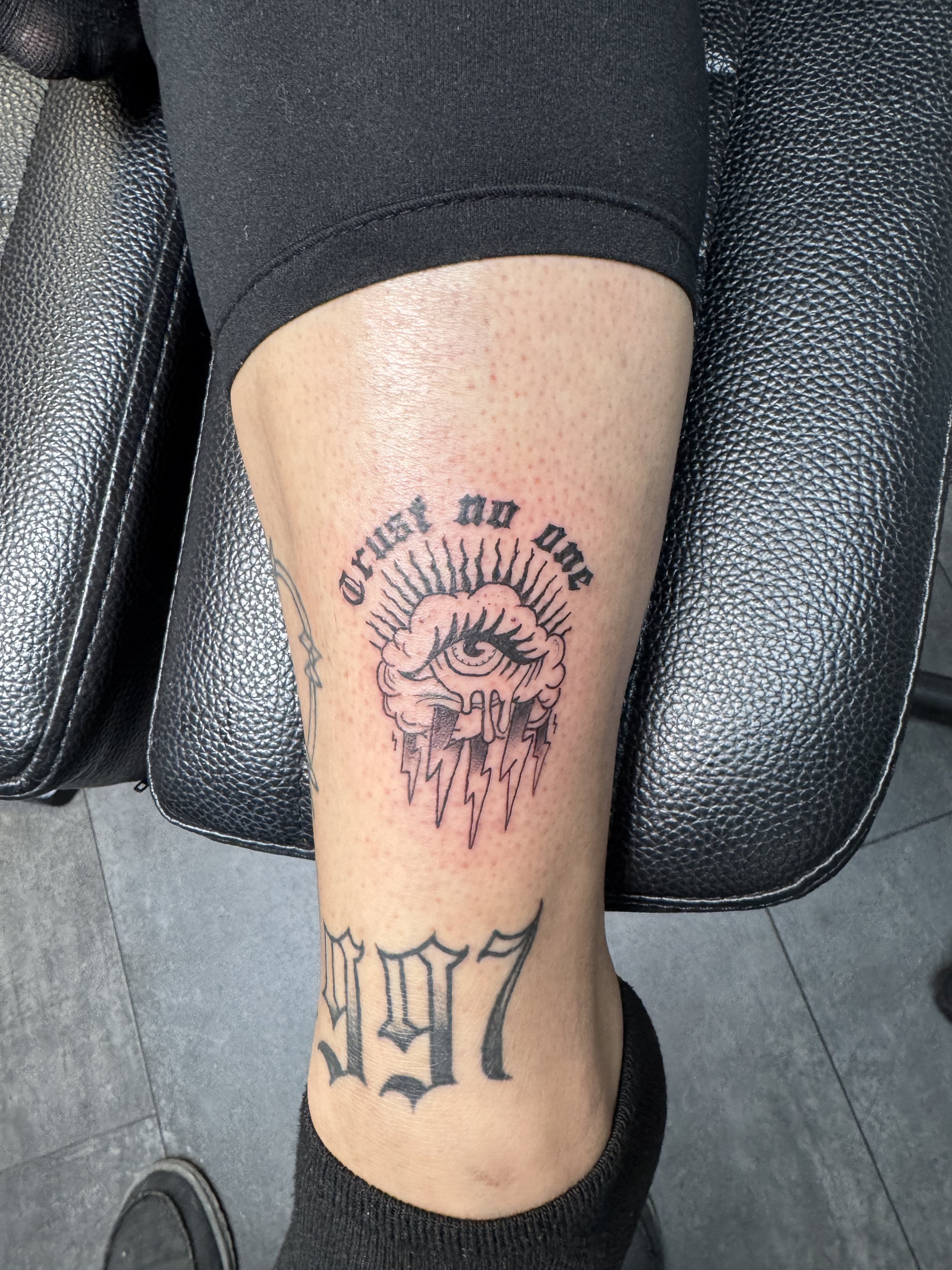 Tattoo on a person's leg featuring an eye surrounded by lightning bolts, with the phrase 'Choose Do One' above, and the numbers '1979' below.