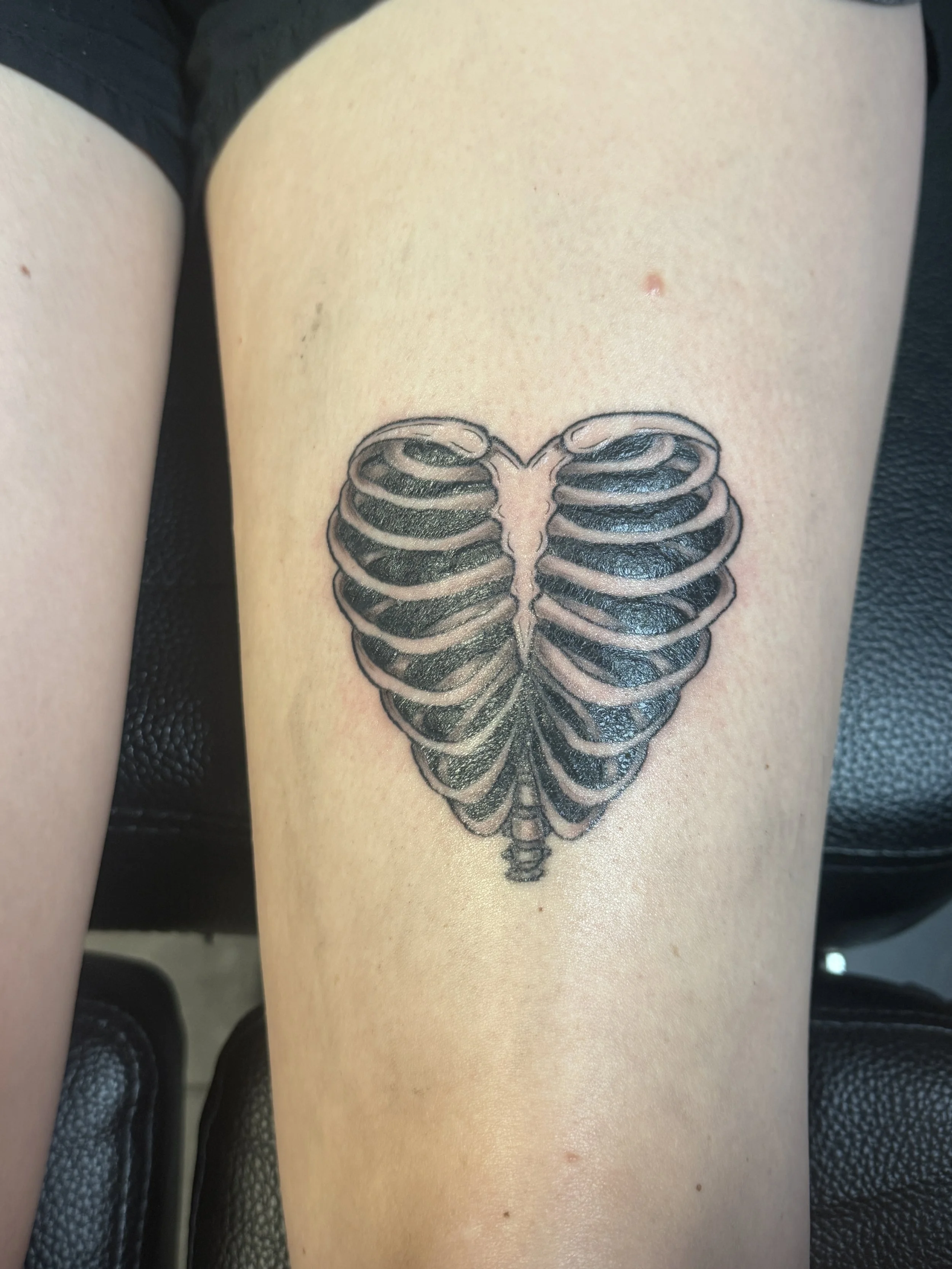Tattoo of a butterfly made from ribcage bones on a person's thigh.
