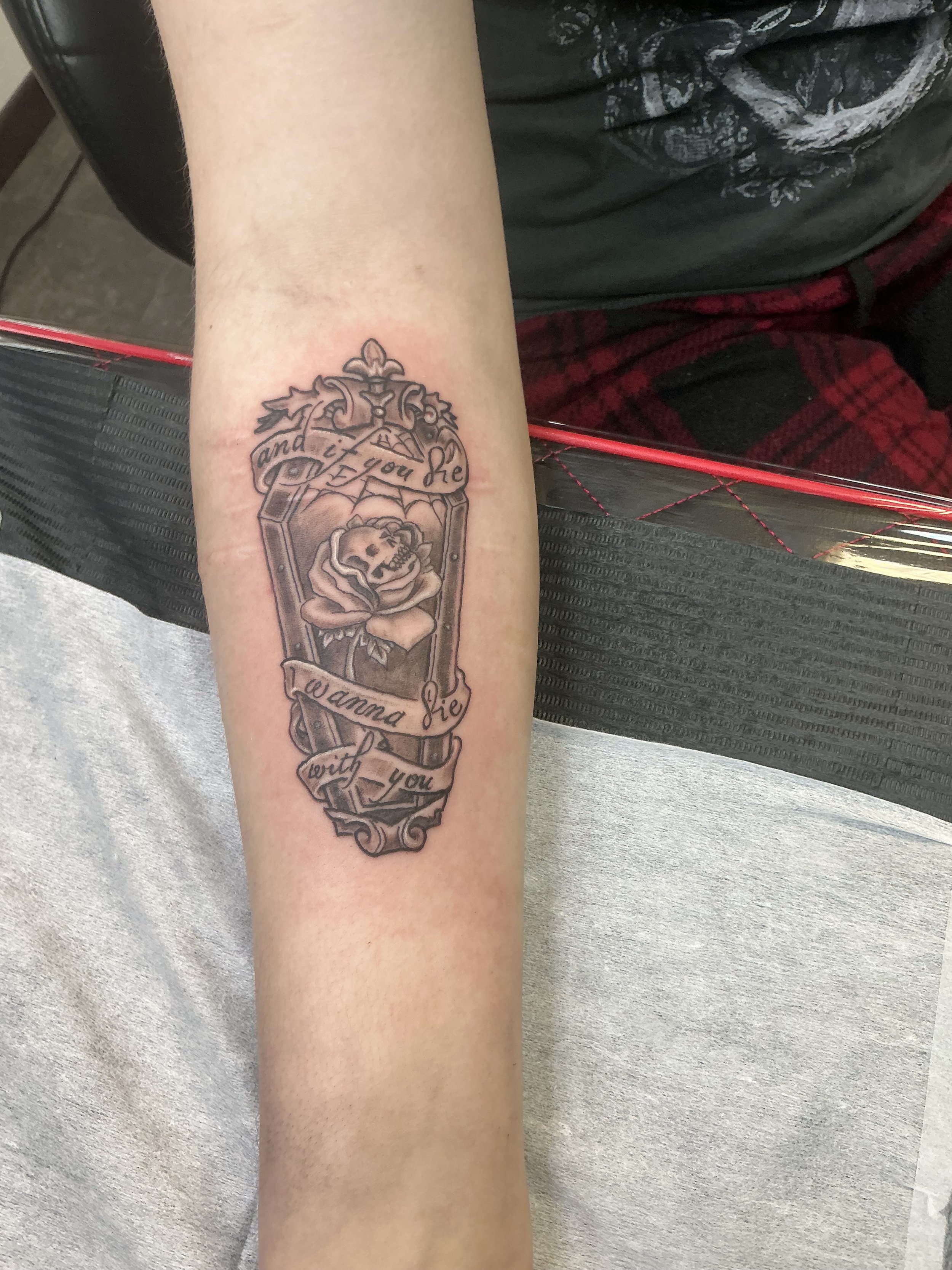 Tattoo of a coffin with a skull and a rose, surrounded by a banner that reads 'and if you die I wanna die with you'.