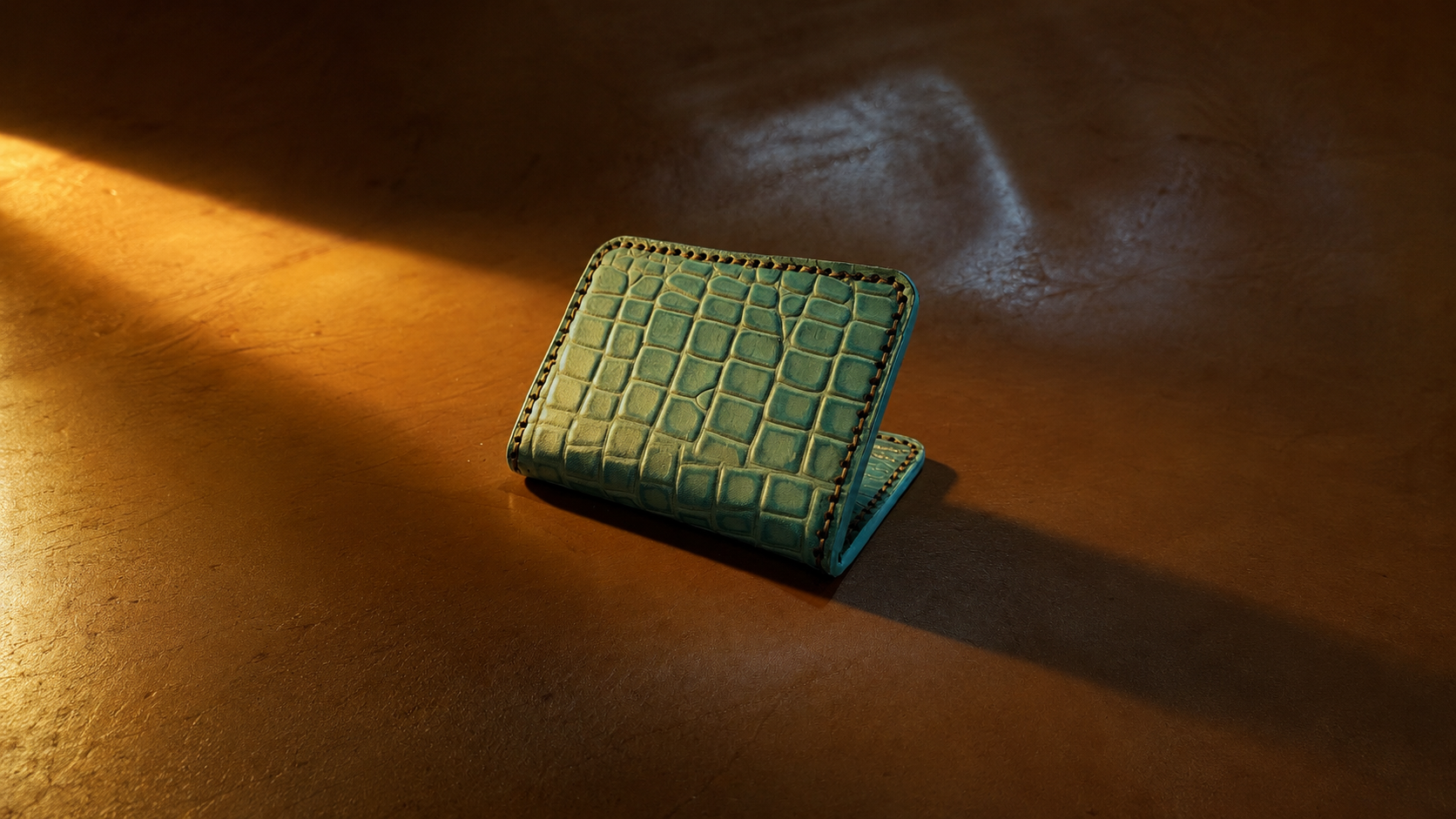 A teal, crocodile-patterned wallet sitting on a wooden surface with warm lighting and a shadow cast to the right.