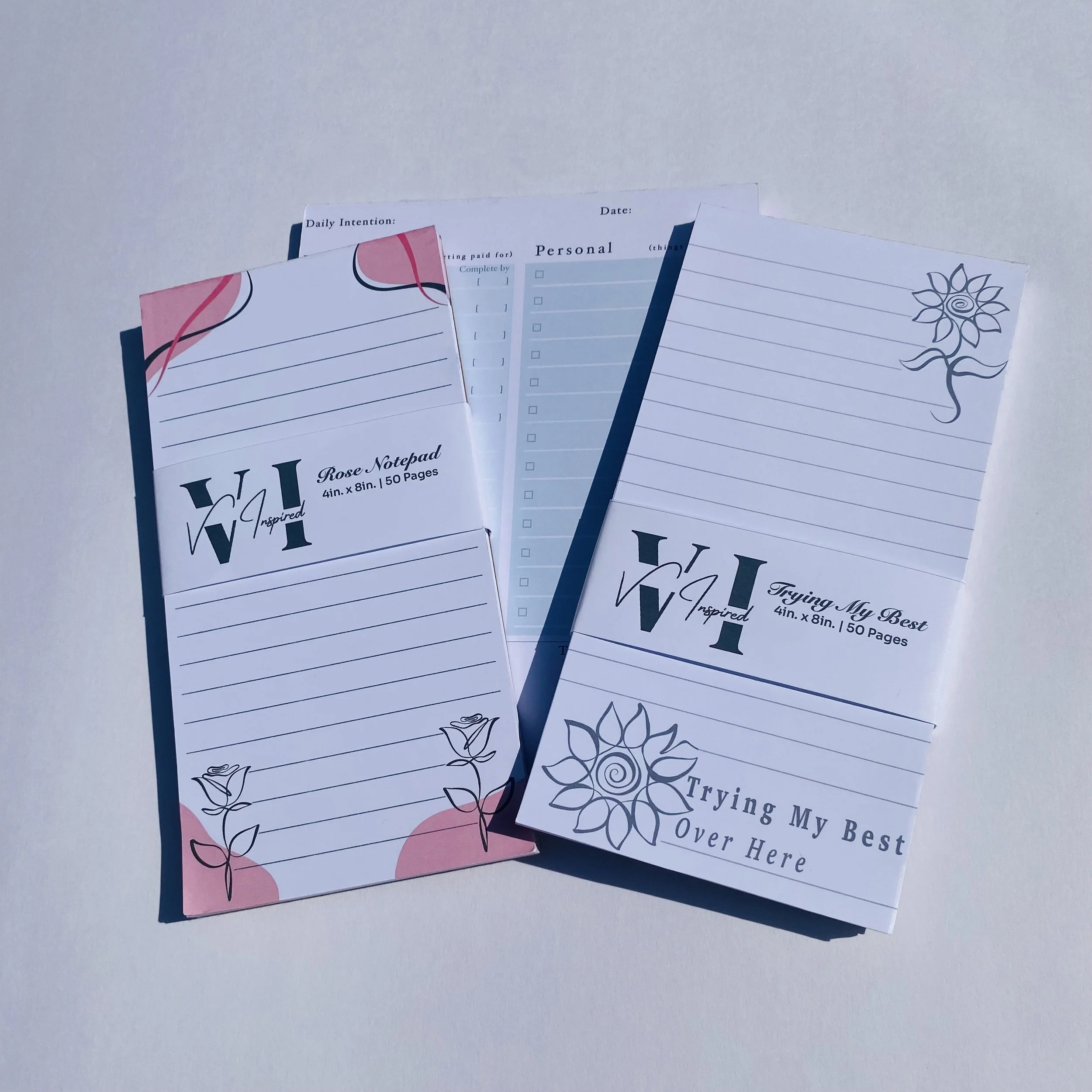Pink and white handmade notepad with floral decorations and lines for writing, labeled as Rose Notepad, measuring 4 inches by 8 inches with 50 pages.