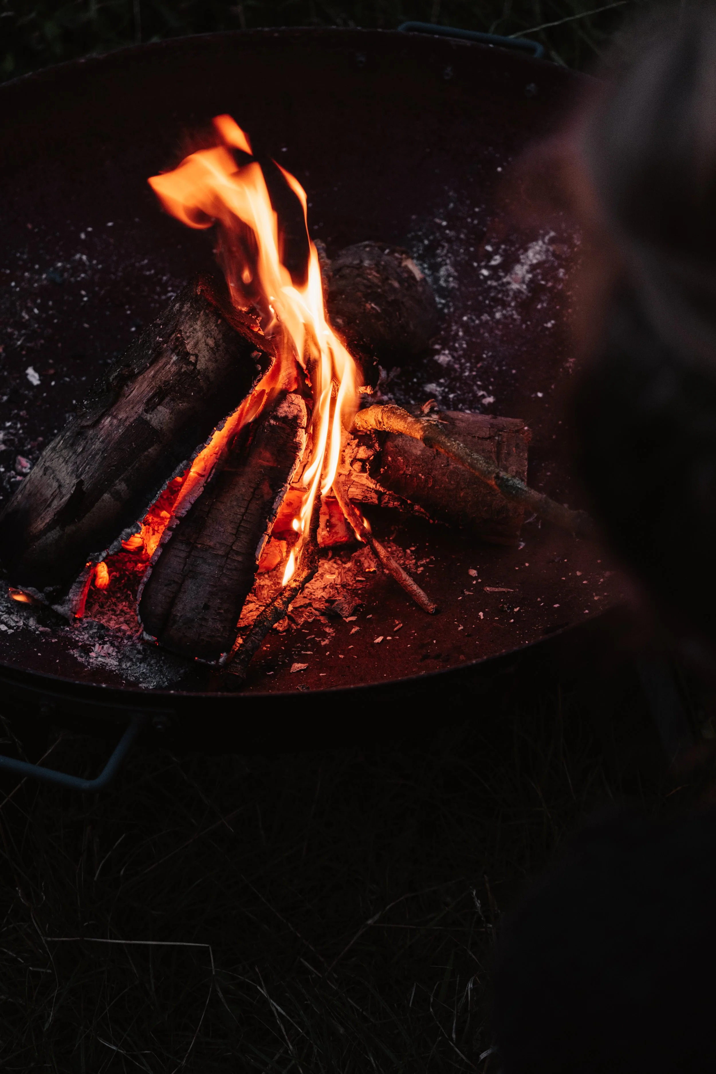 Burning logs in a fire pit at night.