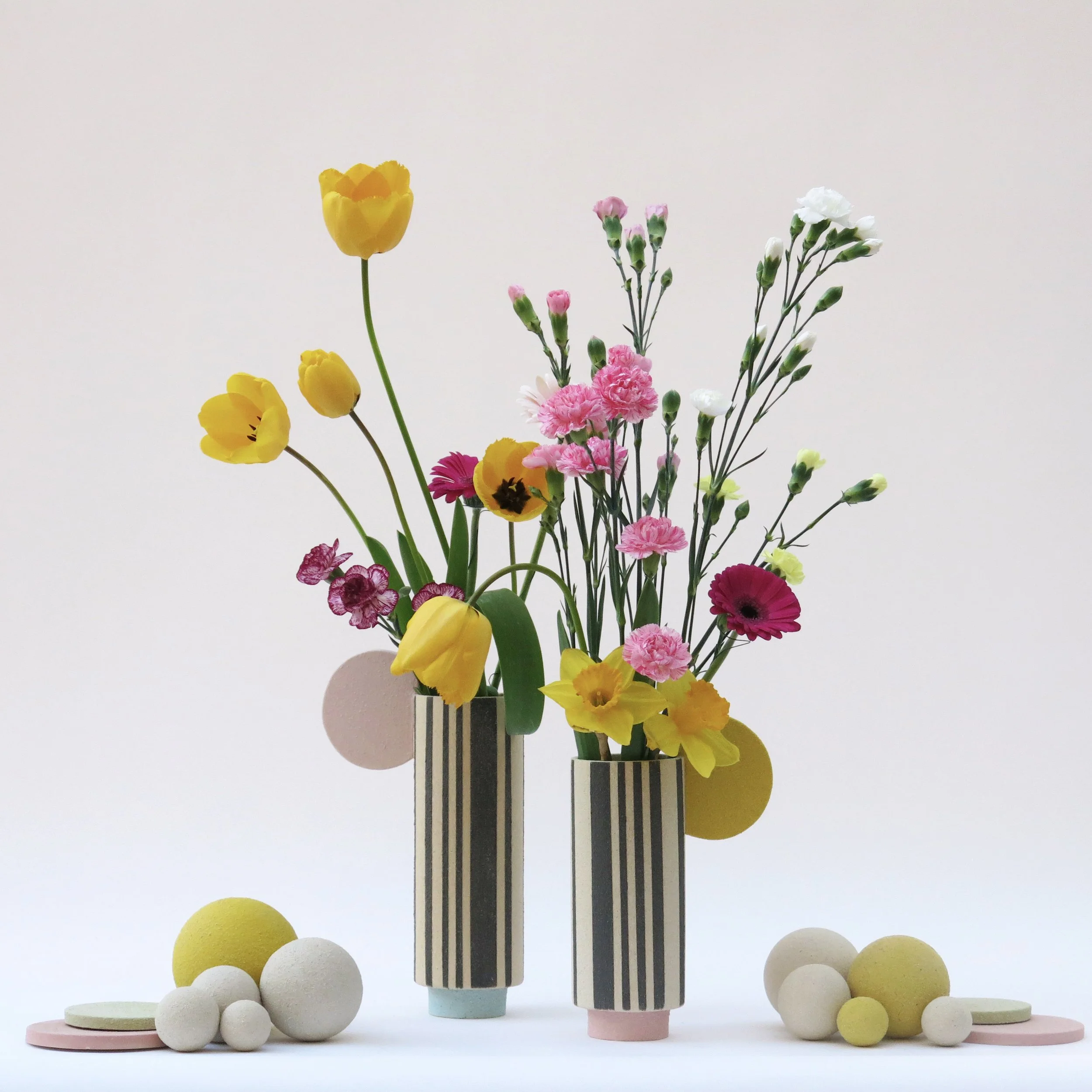 Composition de vases Colonnes en grès chamotté avec décor à l’engobe, lignes noires et éléments colorés, présentés avec fleurs, Julie-Zoé Michel – The Way of Dot.