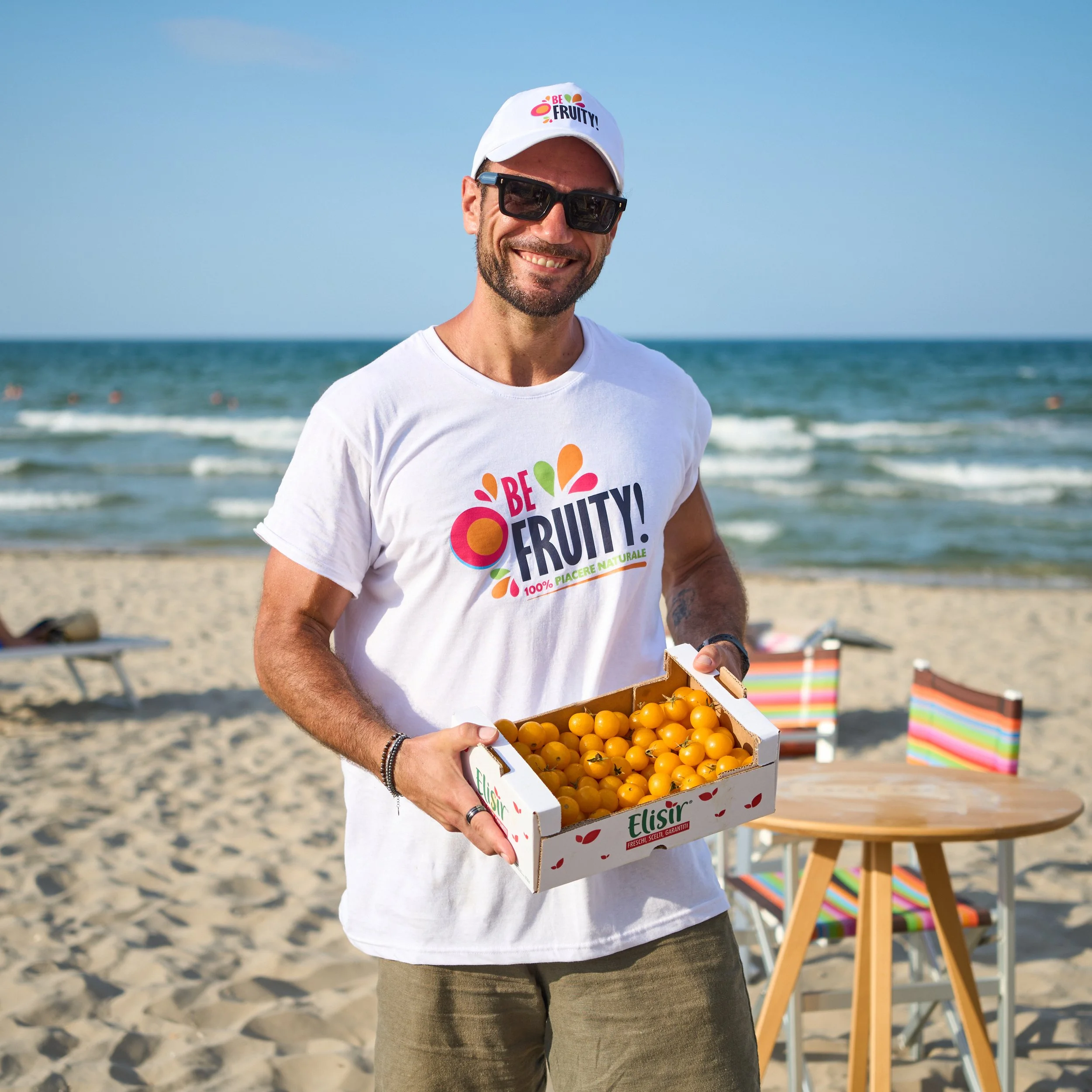 Staff handing out fresh fruit to beachgoers under umbrellas in Rimini