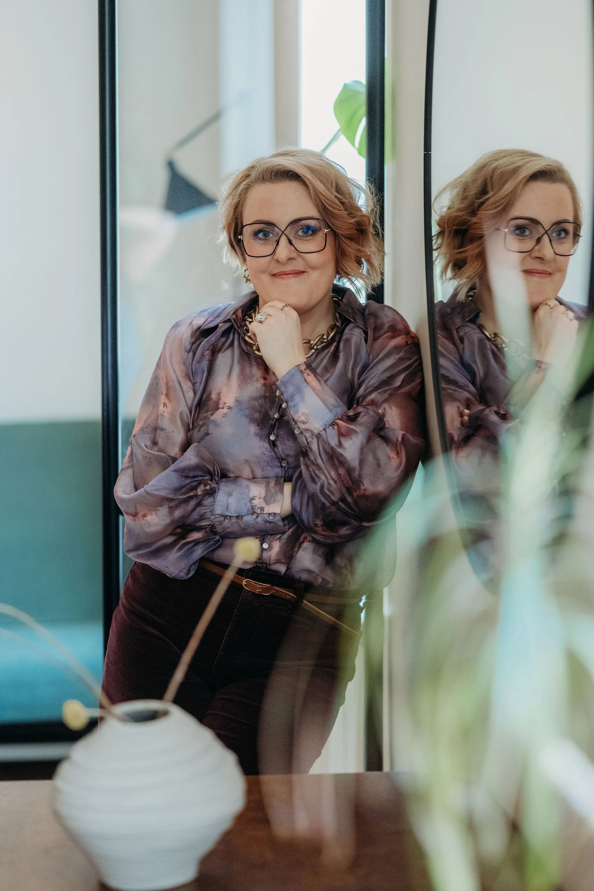 Anna Haverinen, nainen mustasankaisissa silmälaseissa hymyilee kohti kameraa, käsi leuan alla.