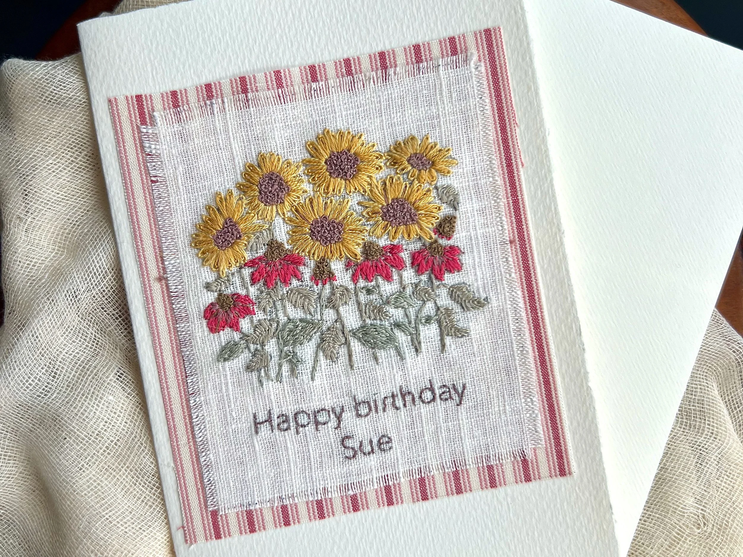 Handmade birthday card with embroidered sunflowers and echinacea, and the message "Happy birthday Sue".