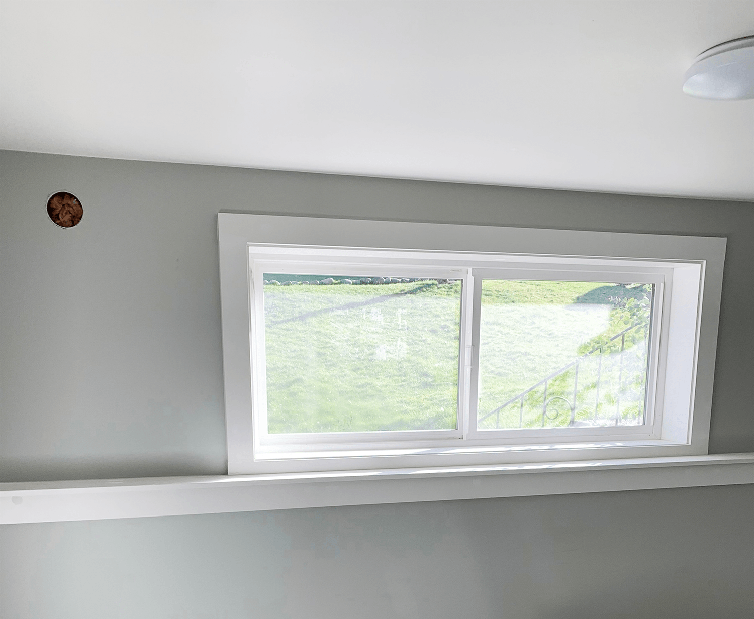 White window trim and casing installed around a basement window, finished with a smooth sill and fresh paint
