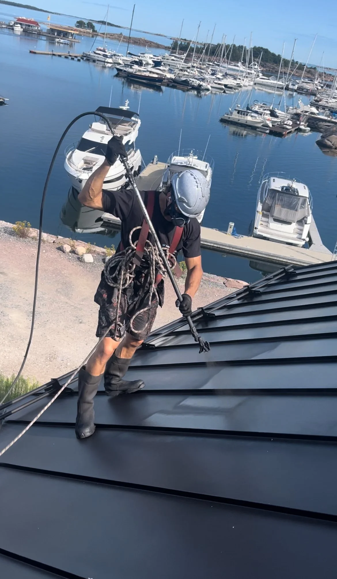 Katon pinnoittaja levittää ruiskulla toista maalikerrosta sinkittyyn peltiin