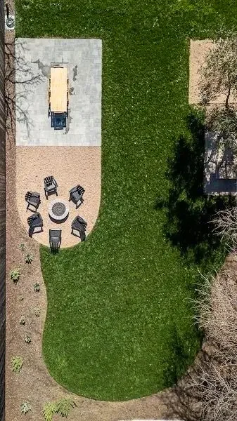 Aerial view of a landscaped backyard featuring a curved lawn, decomposed granite fire pit seating area, and stone patio designed by Legacy Landscape & Arboriculture in Los Alamos, Santa Barbara County