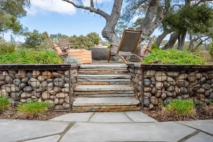 Custom flagstone steps flanked by gabion stone retaining walls leading to an outdoor seating area designed by Legacy Landscape & Arboriculture in Santa Barbara County