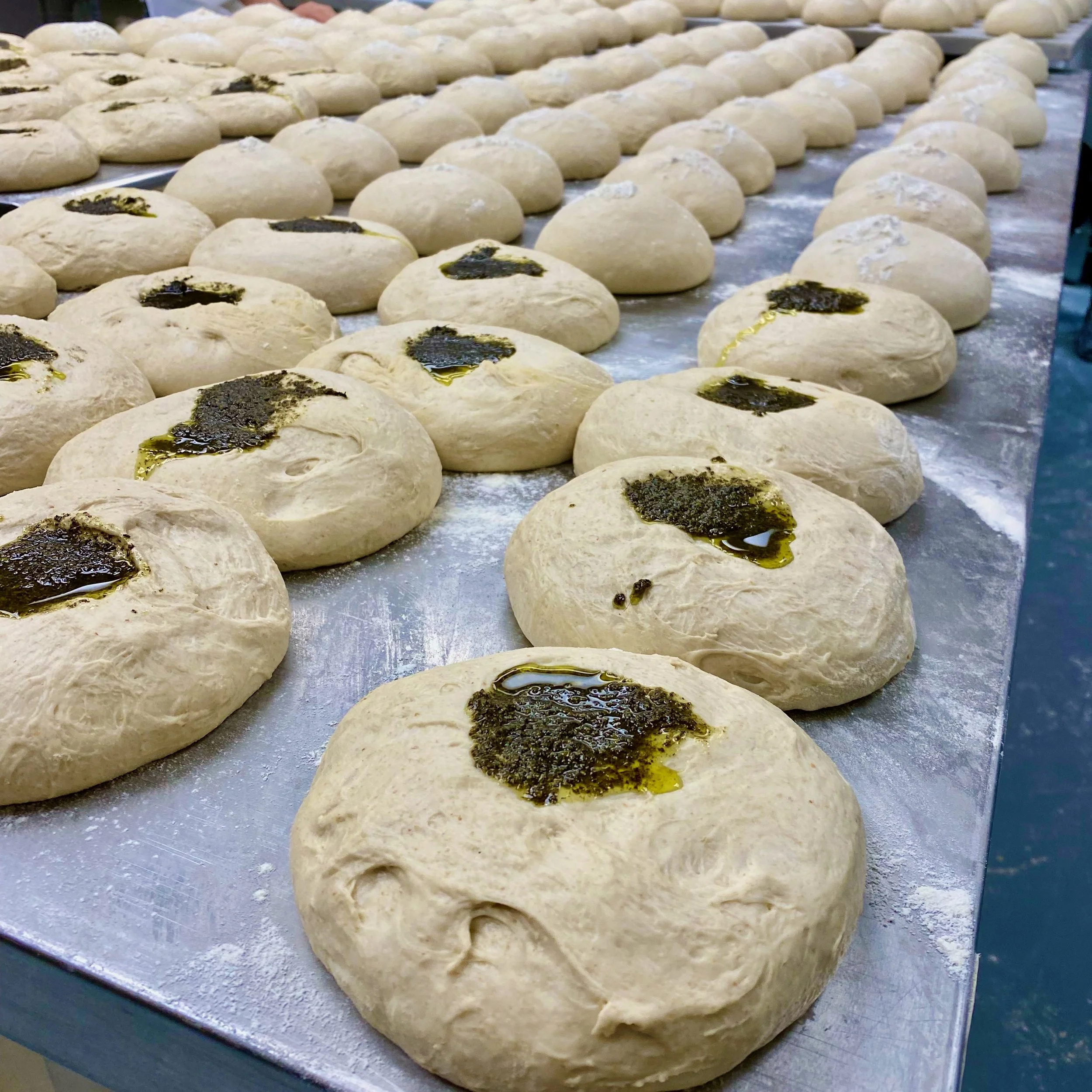 Rows of sourdough portions topped with rosemary and lemon mixture at The Baker & The Cakemaker in Auburn, California