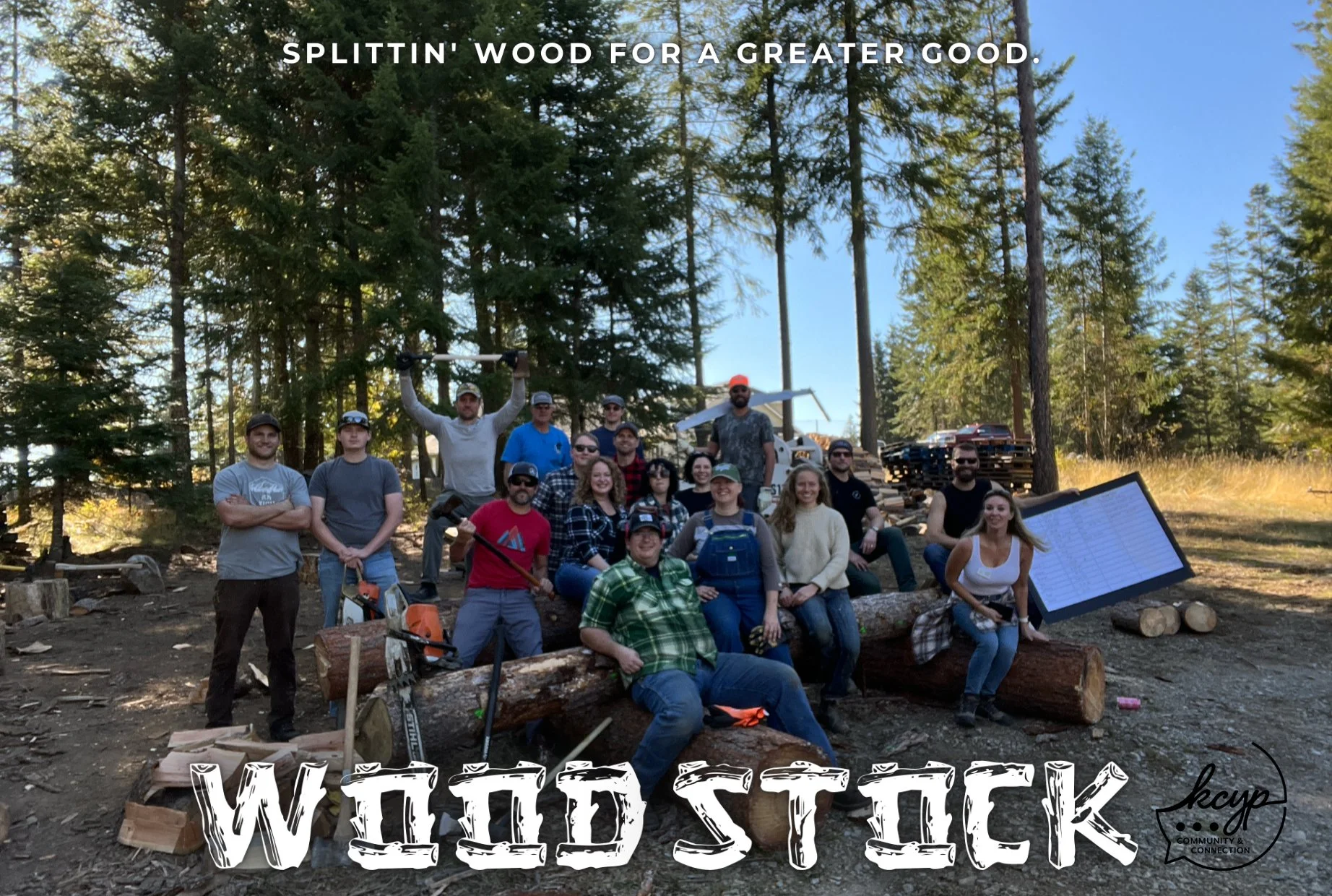 A group of people outdoors in a forested area, sitting and standing on logs and dirt, with trees and a clear blue sky in the background. Some are holding tools like axes, and there are stacks of wood and a large clipboard nearby. The text on the imag