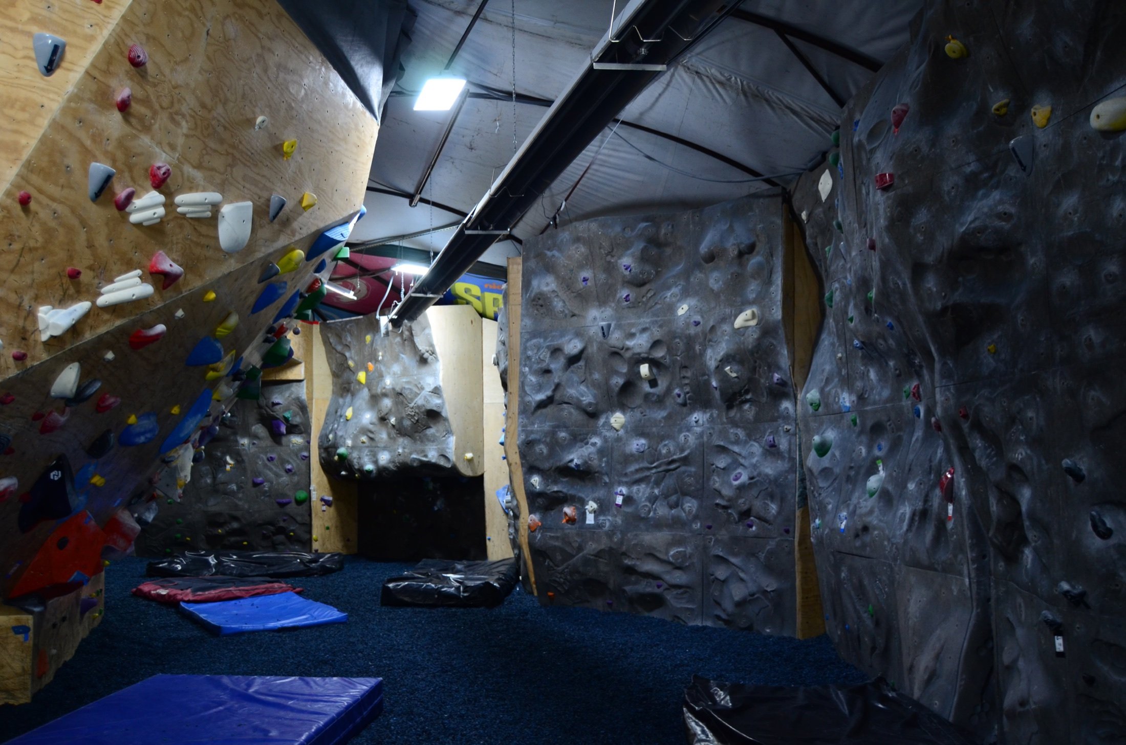 Indoor rock climbing gym with artificial climbing walls covered in colorful holds and padded flooring.