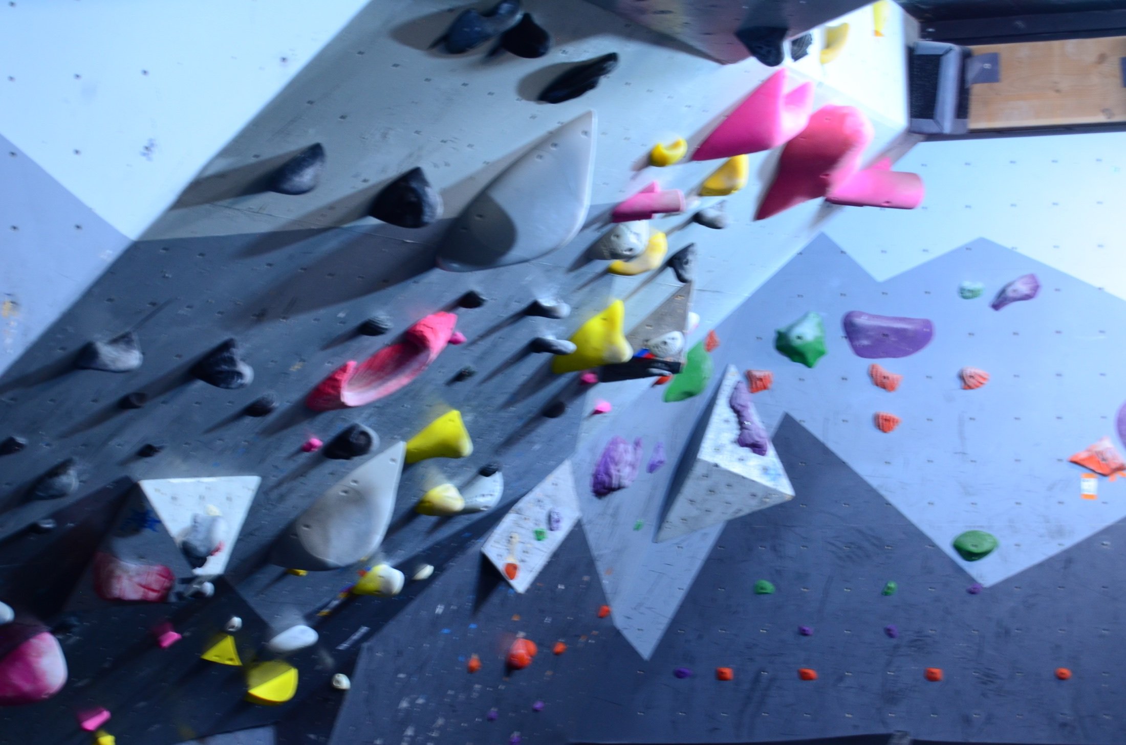 Indoor bouldering gym with various colored climbing holds on a gray climbing wall.