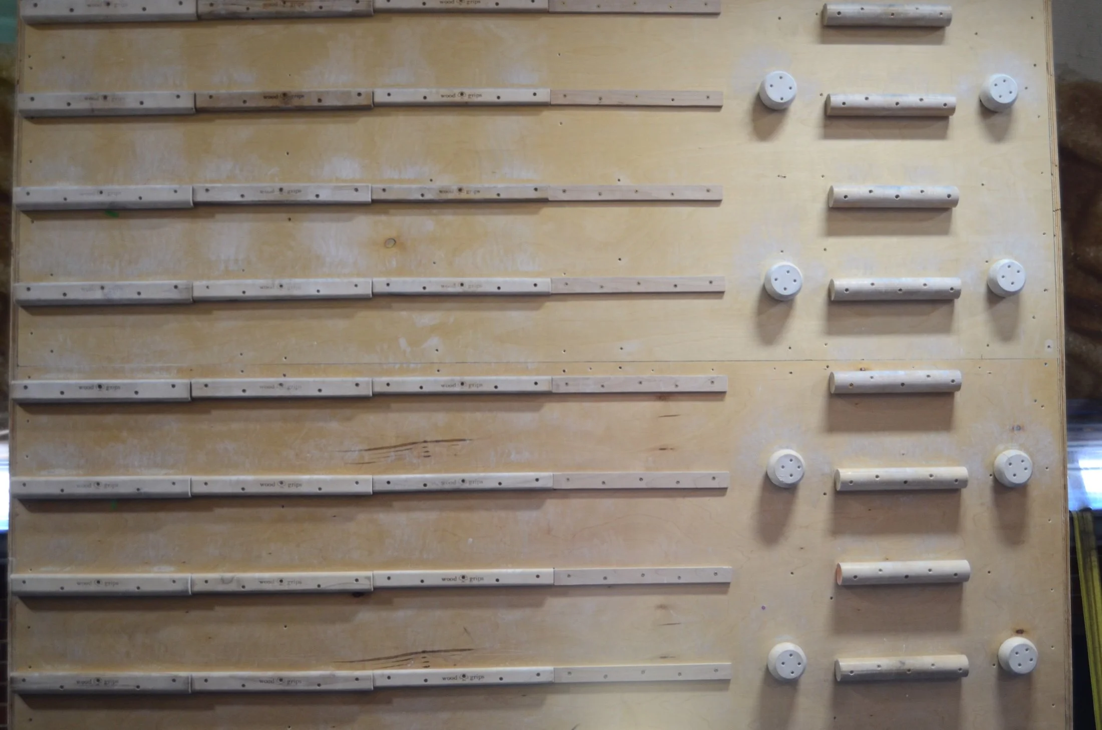 A wooden pegboard with horizontally aligned wooden strips and cylindrical holders.