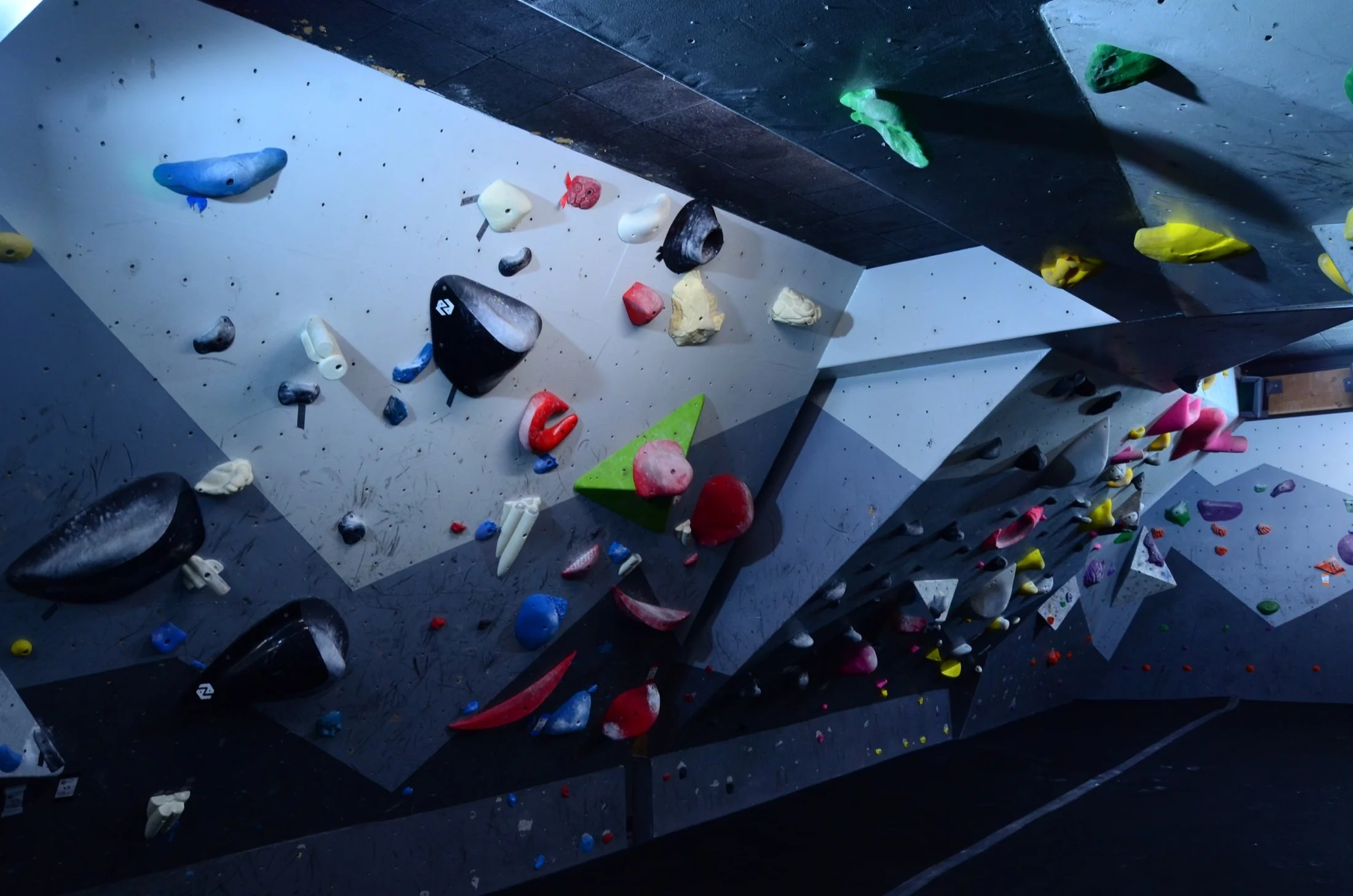 Indoor bouldering climbing gym with various colorful holds on the walls for climbing.