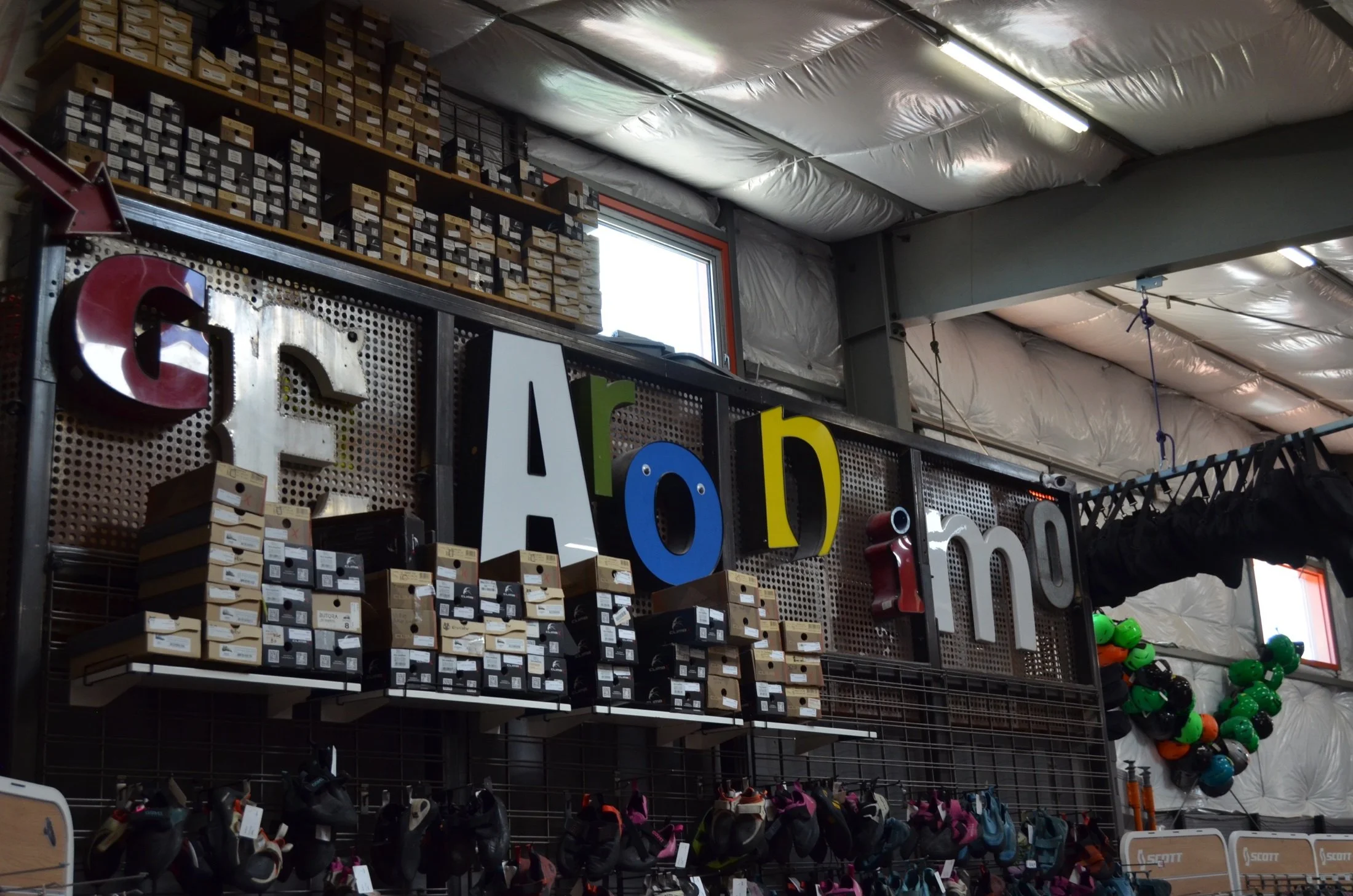 Display of athletic shoes, helmets, and boxes on industrial-style shelves inside a sports store.