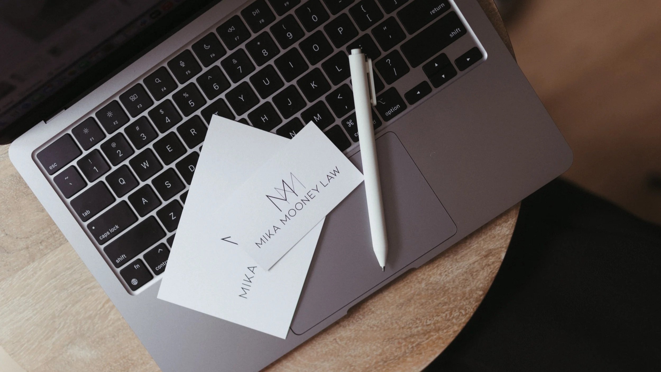 Business cards, laptop, and stylus on a desk representing the decision to register for copyright protection with trusted legal counsel from Mika Mooney Law.