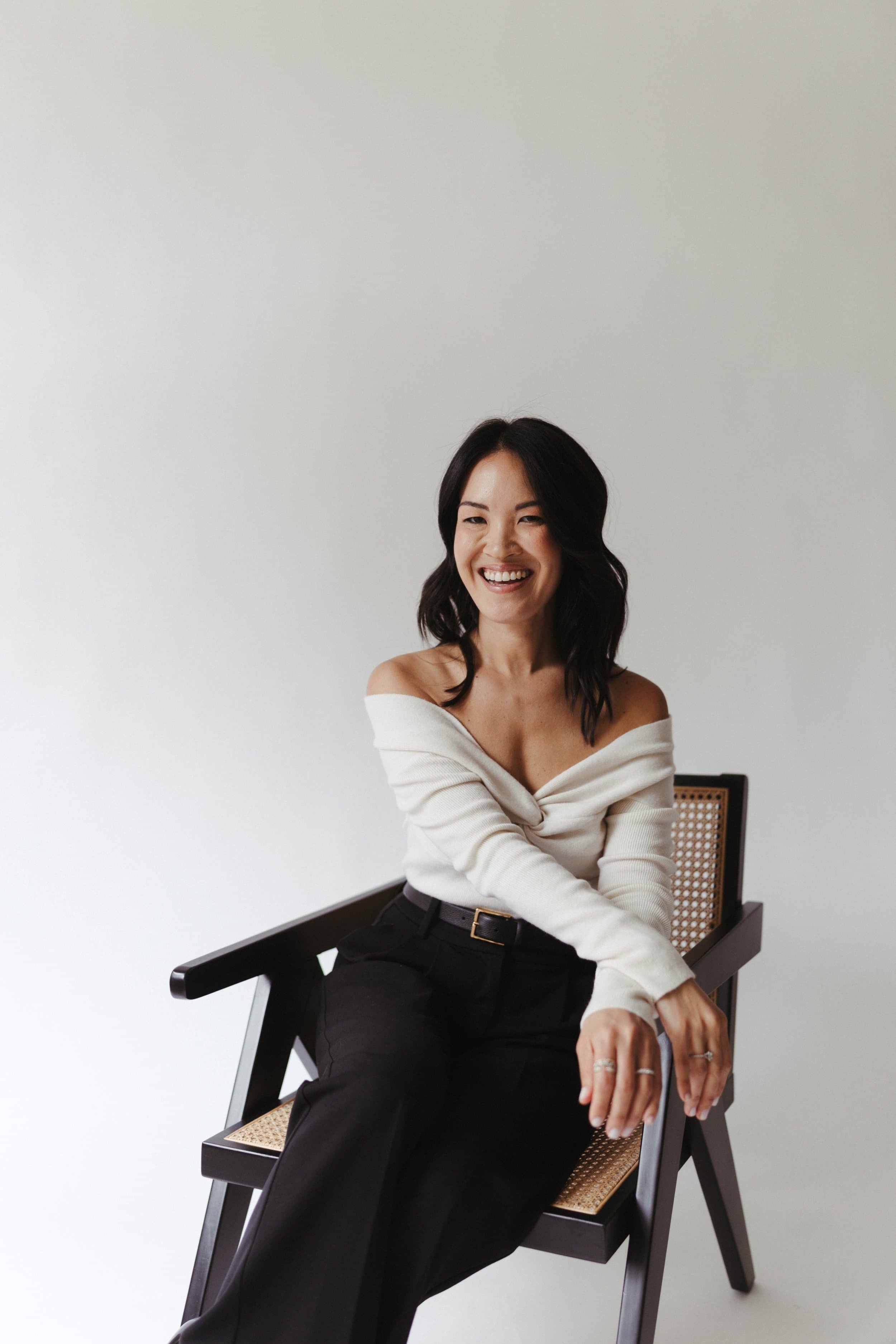 Mika Mooney smiling in a modern chair during a professional branding photoshoot for her law firm, Mika Mooney Law.