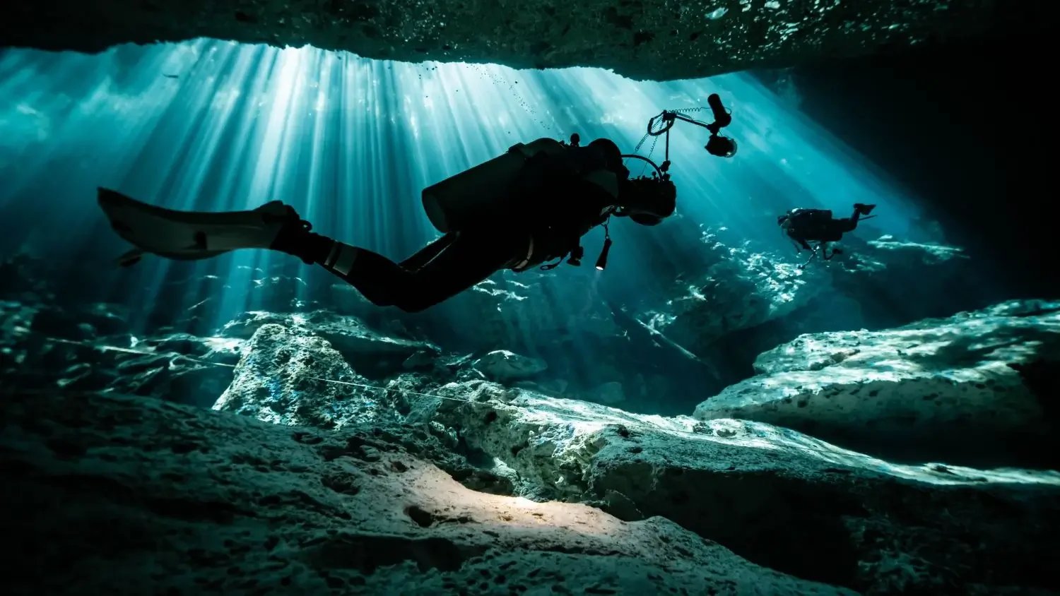Scuba diver exploring crystal-clear cenote in the Yucatán Peninsula looking for the perfect photograph