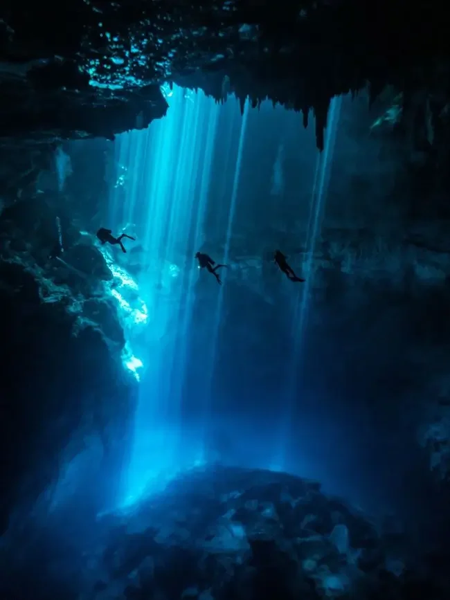 Three divers descending into El Pit Cenote in Mexico's Yucatan