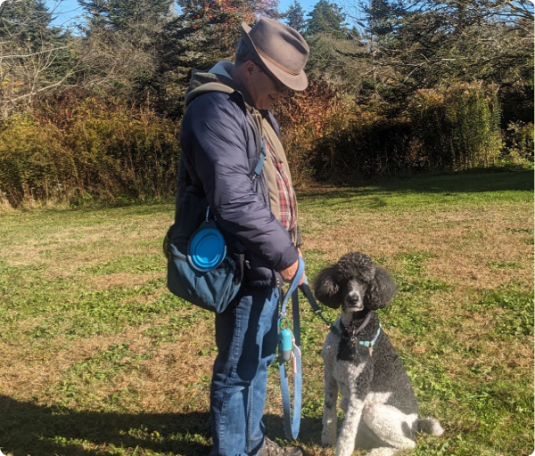A man is looking down at his poodle during a private training session