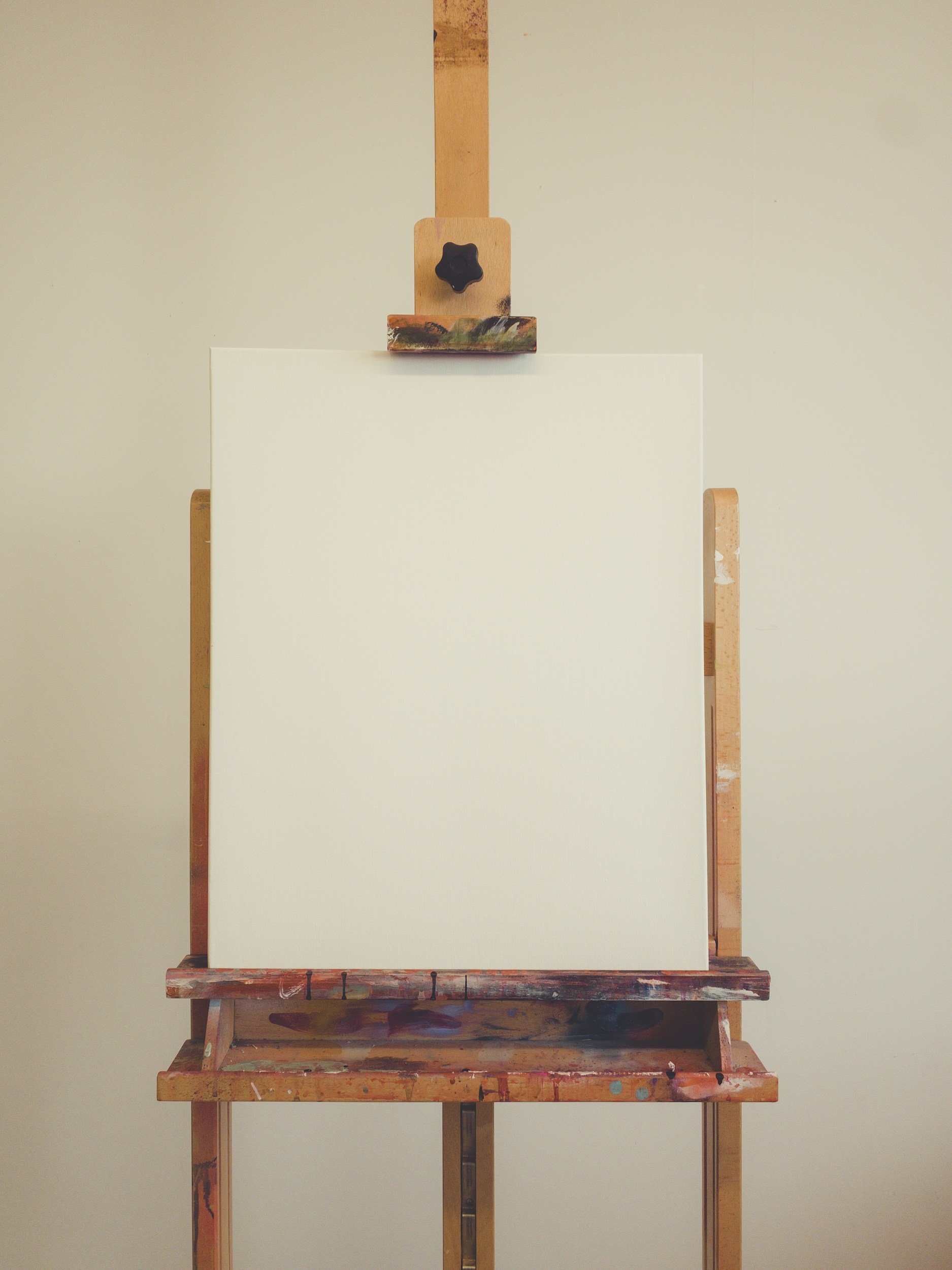 Blank white canvas on an easel in an art studio.