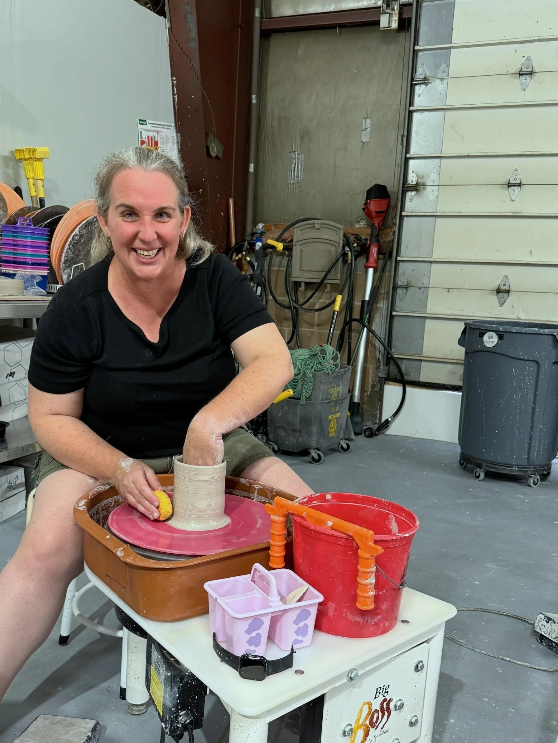 woman smiling throwing on the pottery wheel at grit & grog in agawam