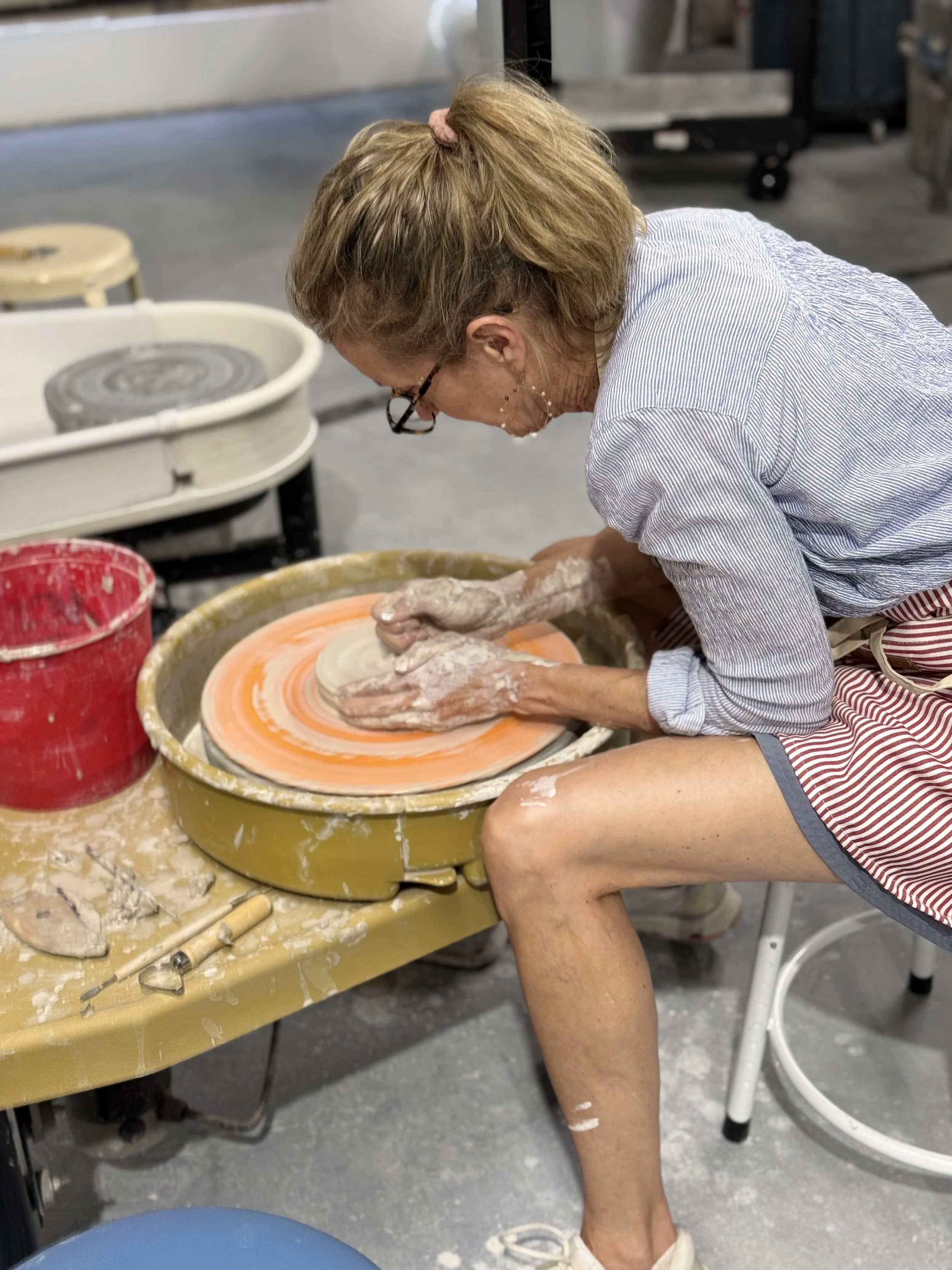 woman centering clay on the pottery wheel at grit & grog in agawam