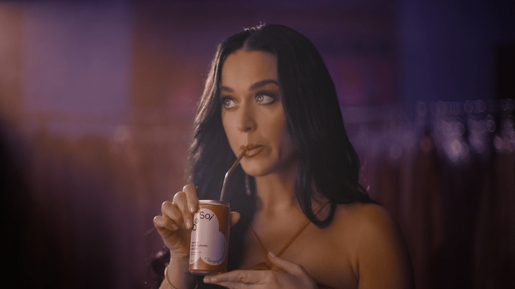 A woman with long dark hair drinking from a small can through a straw.