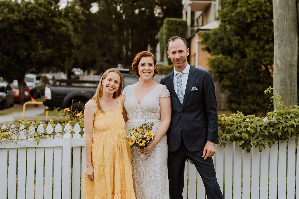 Ellen Carey Marriage Celebrant standing with newlyweds Sam and Mike after officiating their intimate wedding / elopement in at their home. Backyard wedding. Intimate wedding. Marriage Celebrant Brisbane. Relaxed wedding celebrant.