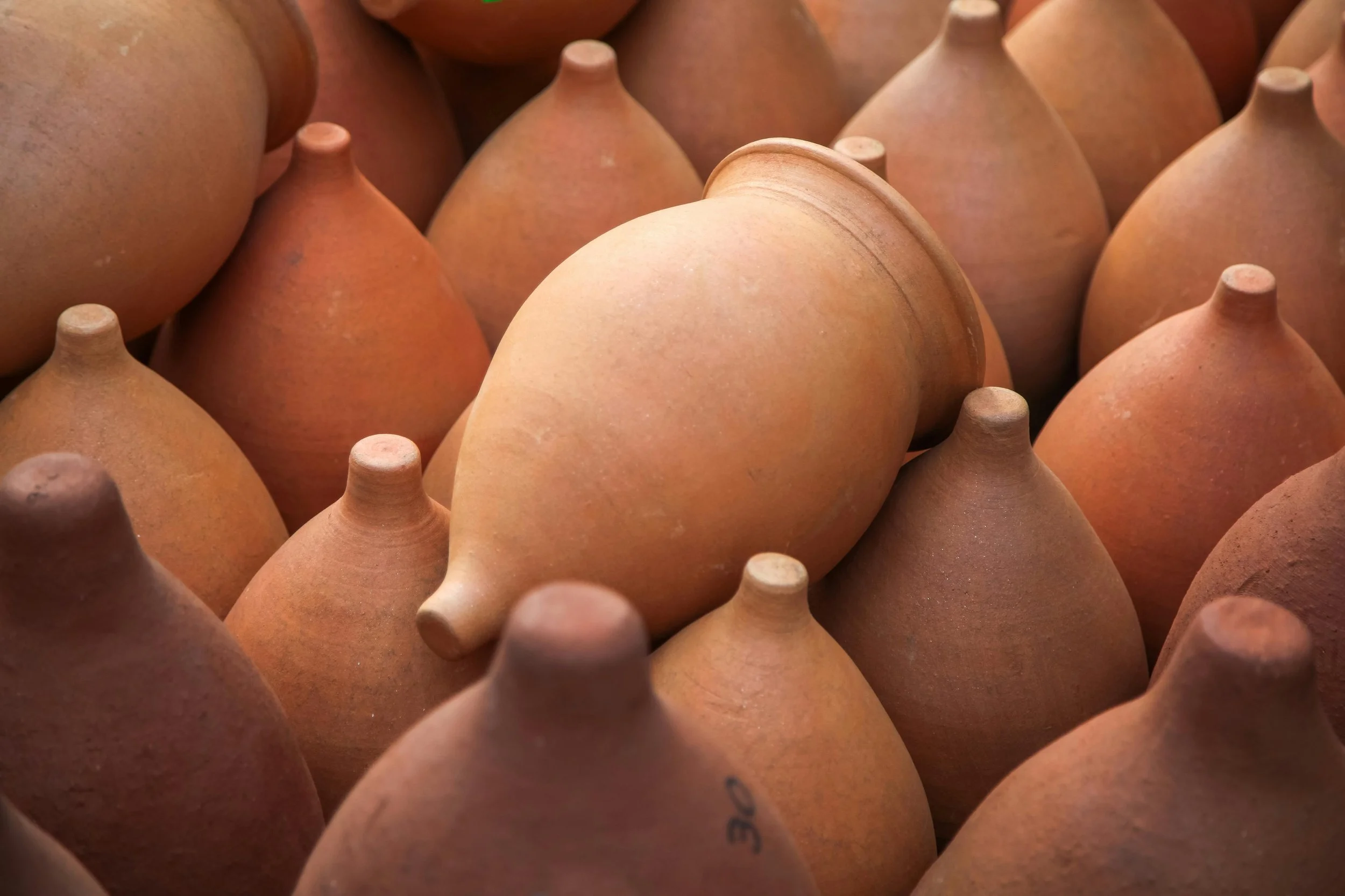 A collection of terracotta pottery with one piece tilted among the others.