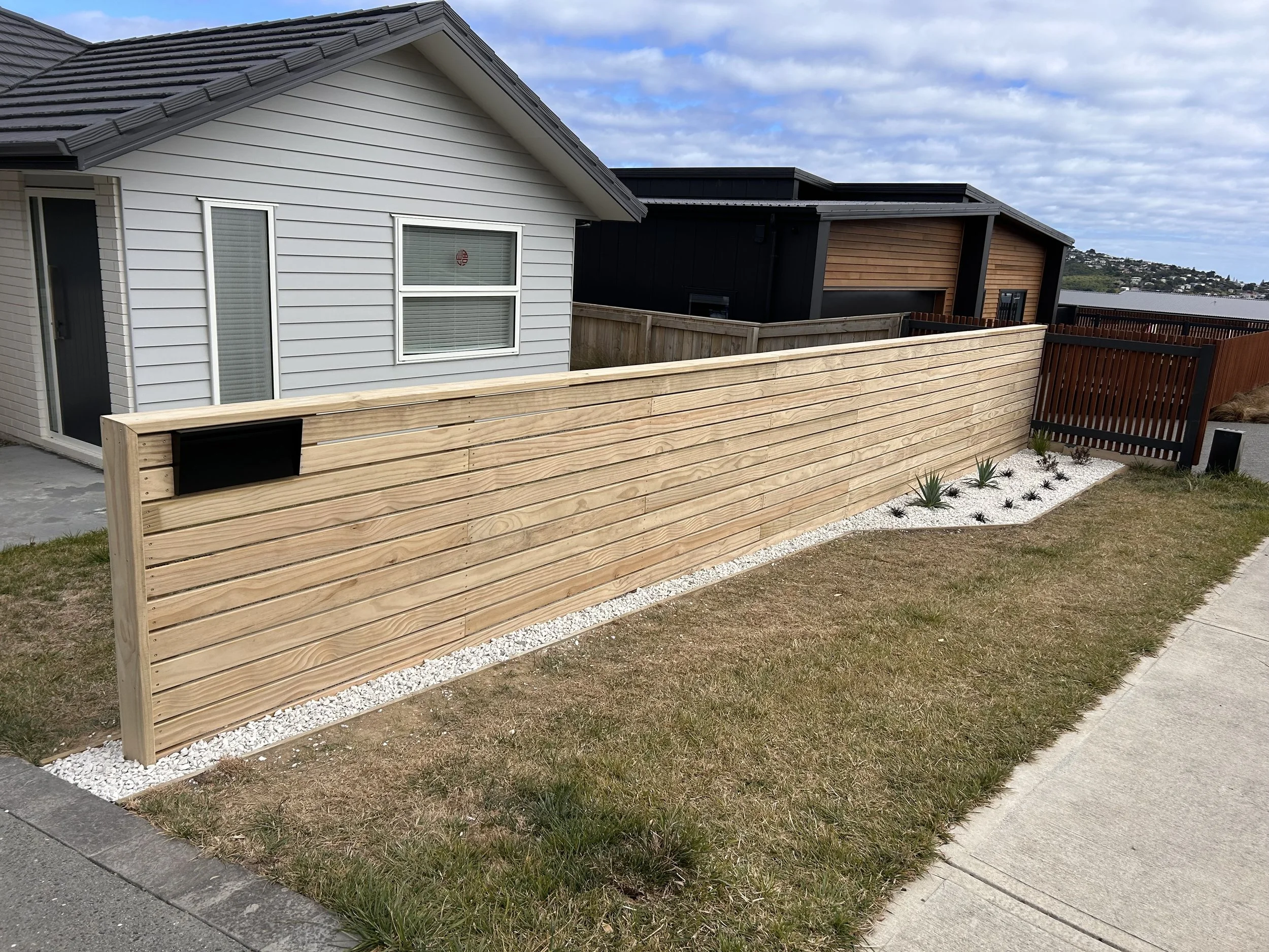 New horizontal decking privacy fence installed, with white stones and native plants