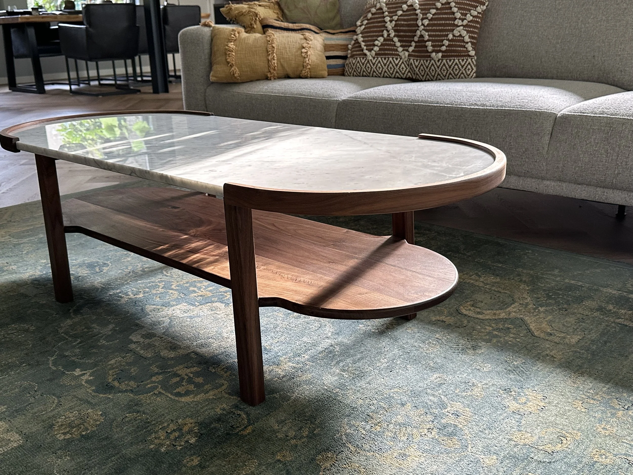 Een salontafel met een bovenblad van marmer en een onderblad van Zwart walnoot hout in een woonkamer.