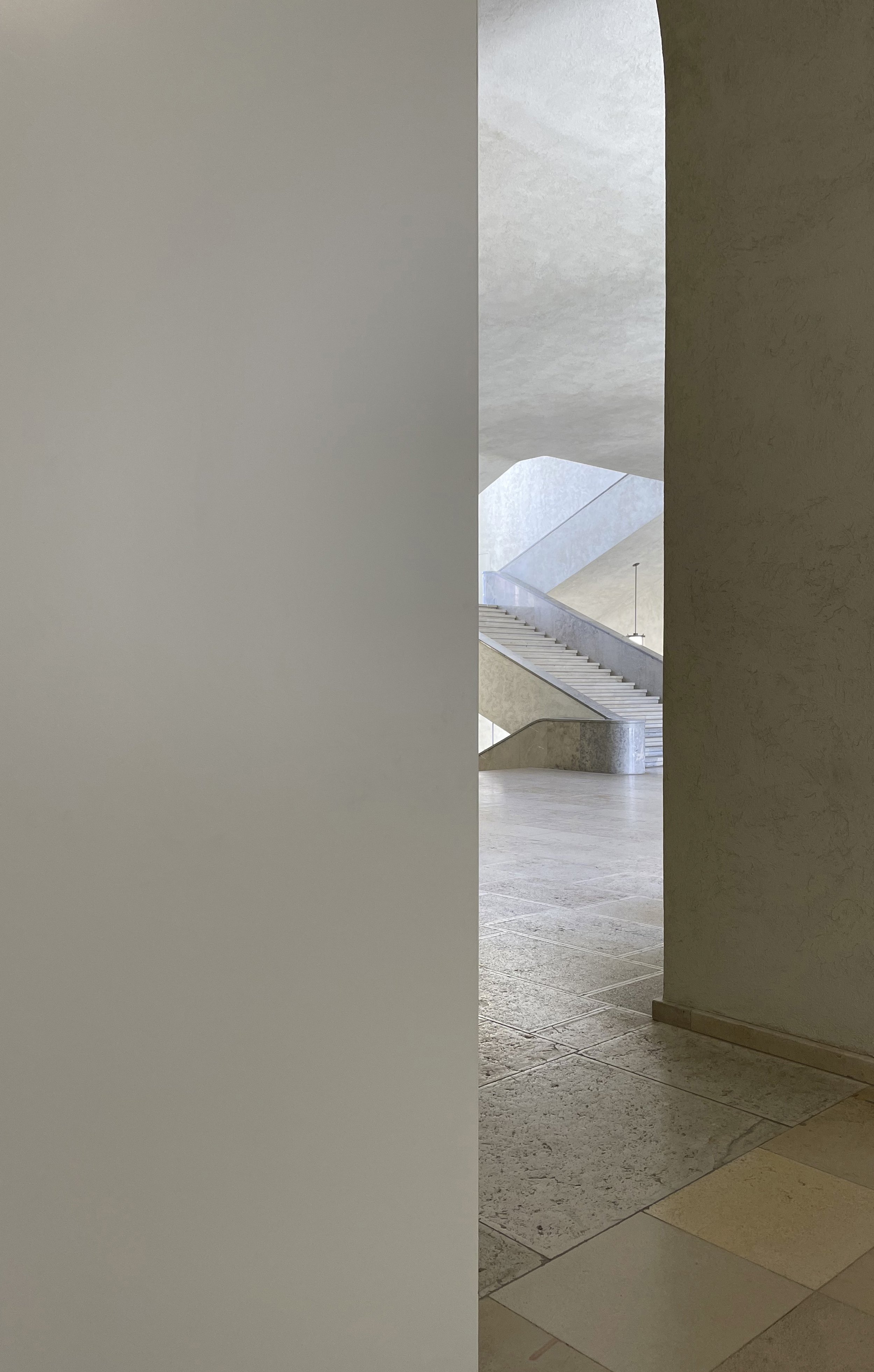View of a staircase with concrete walls and floor, seen through an open doorway in a modern building.